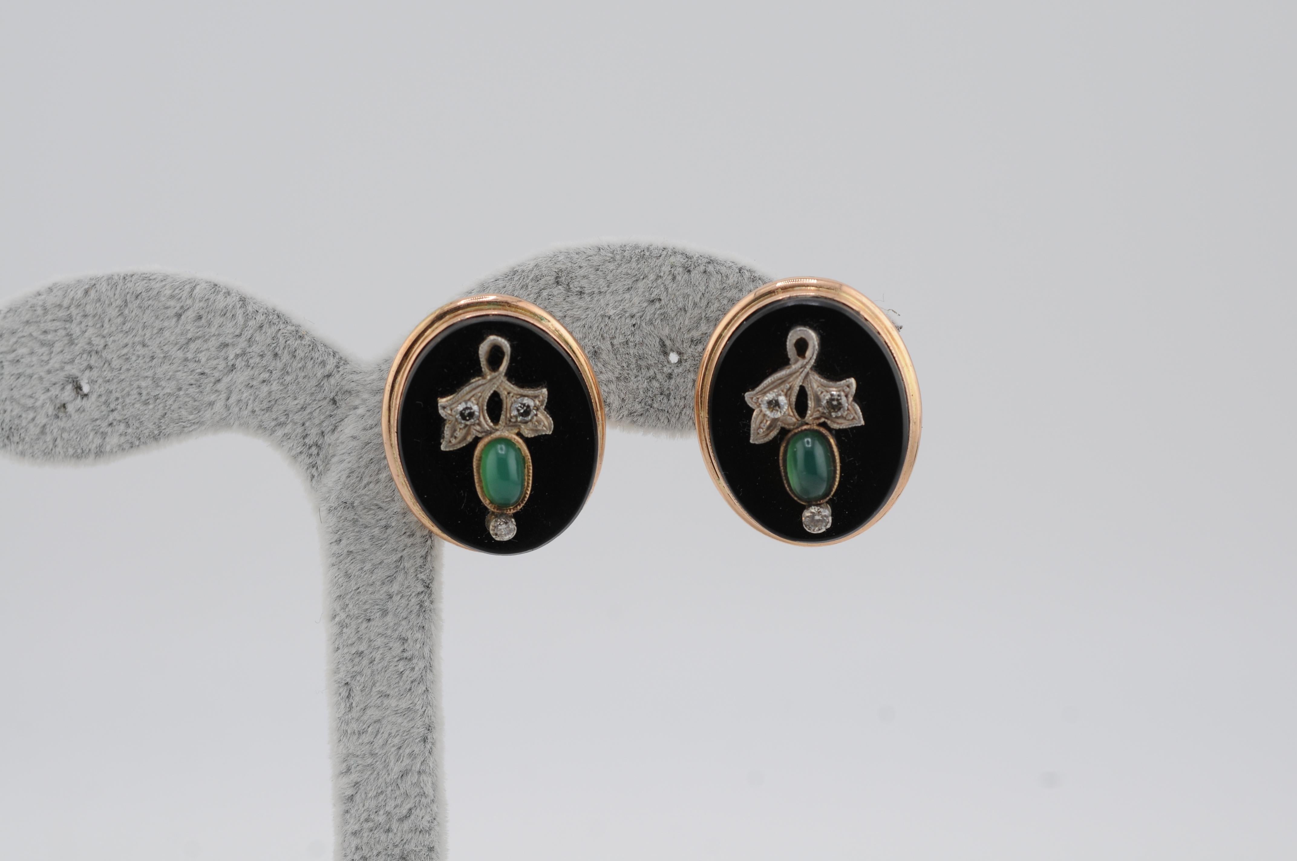 Eleganti orecchini antichi realizzati in oro giallo 14 carati, disegnati a forma di fiori delicati. Ogni pezzo è incastonato con un vibrante smeraldo cabochon al centro, incorniciato da ricchi petali di onice e impreziosito da scintillanti diamanti