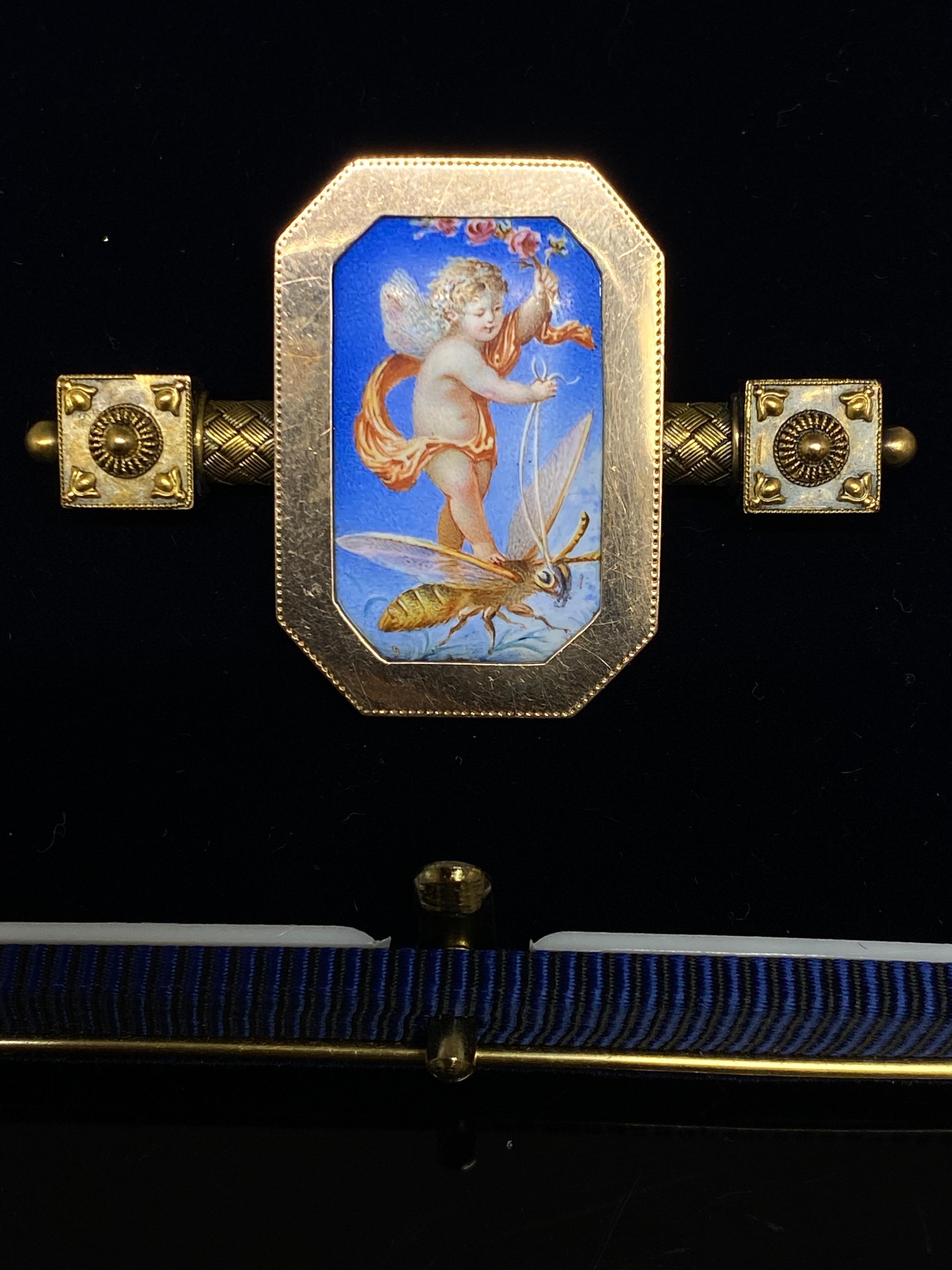 Antique Victorian 14k gold brooch with a stunning hand painted miniature painting on porcelain at the center. An enchanting and delightful little flying cupid, cherub is being drawn atop the wings of a bee.  Absolutely lovely and beautifully