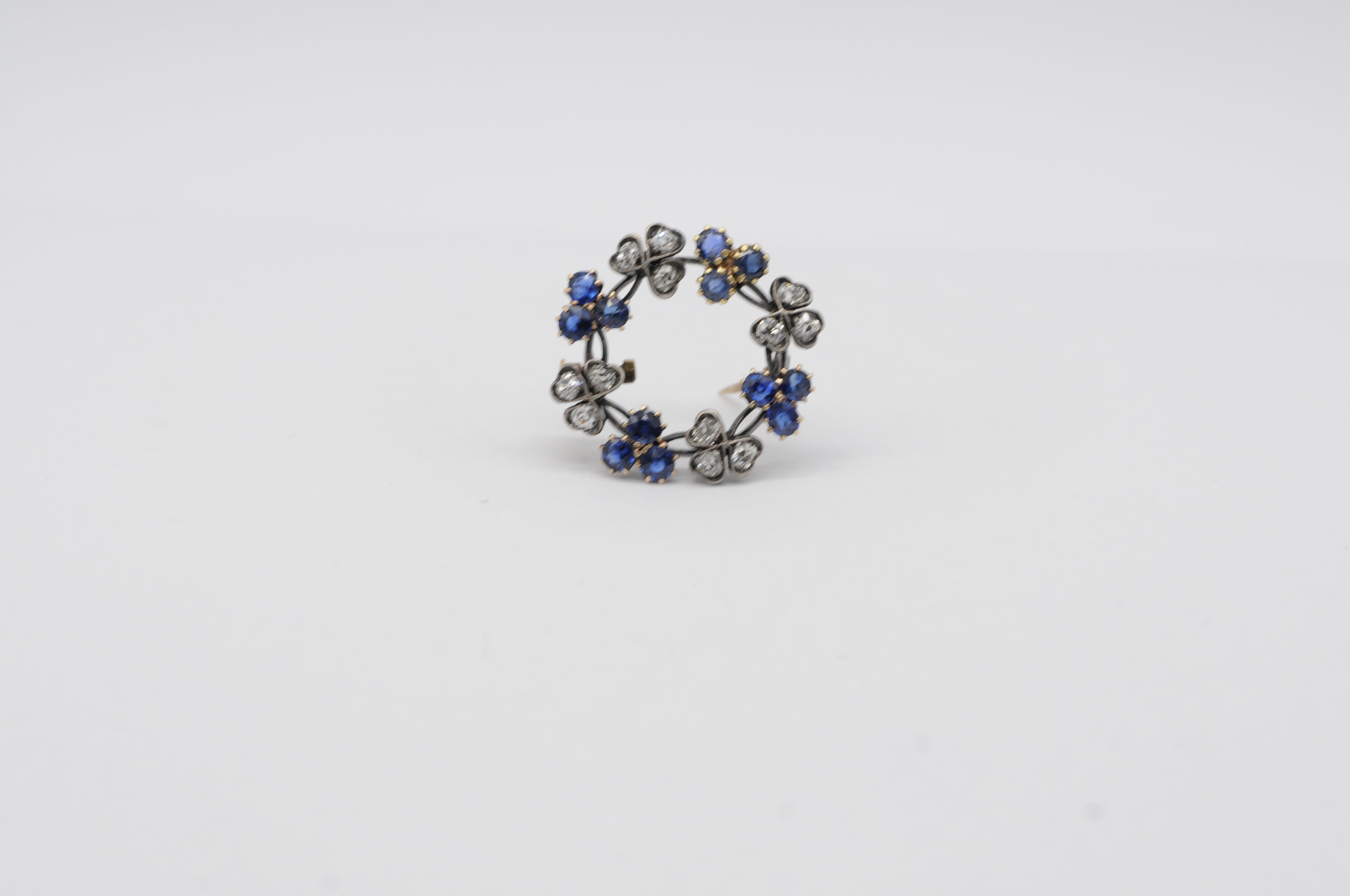 This beautiful antique brooch, crafted in 14k white gold, showcases a classic elegance that transcends time. Set with a stunning array of 12 brilliant-cut diamonds and 12 brilliant-cut sapphires, each gemstone weighs approximately 0.05 carats,