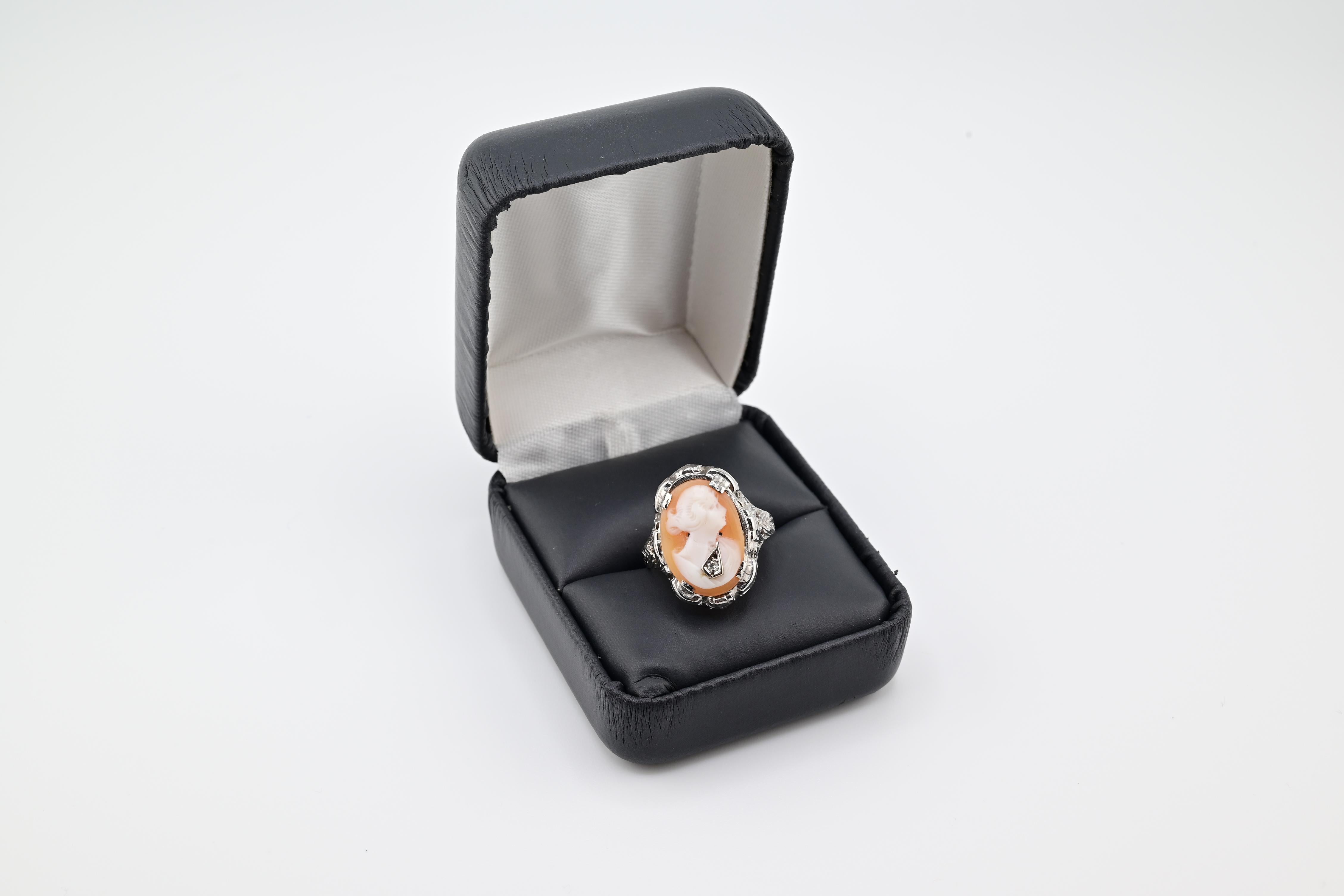 Este anillo antiguo de filigrana es una impresionante pieza de joyería que rezuma estilo victoriano. El anillo es de oro blanco de 14 quilates y lleva un hermoso camafeo de dama de diamantes habille. El intrincado diseño de filigrana se suma al