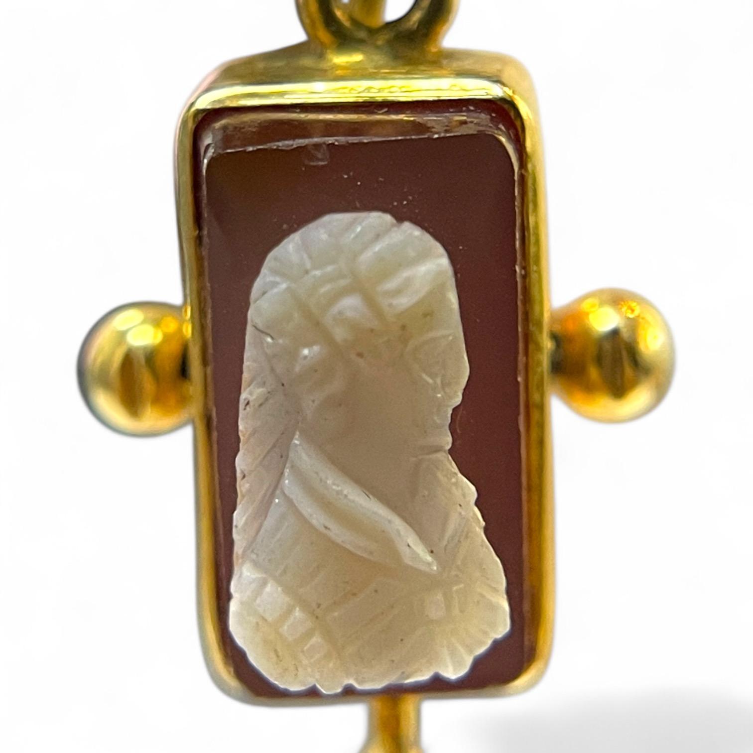 Discover the charm of these exquisite cameo earrings, designed to captivate with their timeless elegance. Each earring features a rectangular cameo, intricately carved with a profile, set in a lustrous gold frame. The cameos are accented with