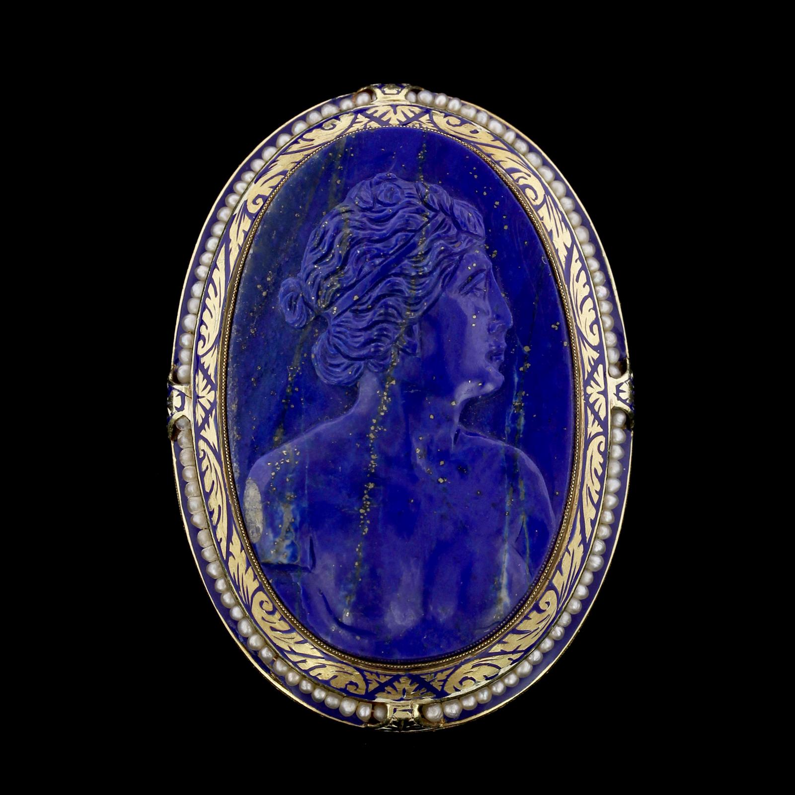 Antique 14K Yellow Gold Carved Lapis Cameo Brooch Pendant. The pin is set with a carved lapis
cameo measuring 45.00 x 28.00mm., framed by seed pearls and blue enamel accents,
length 2 1/8