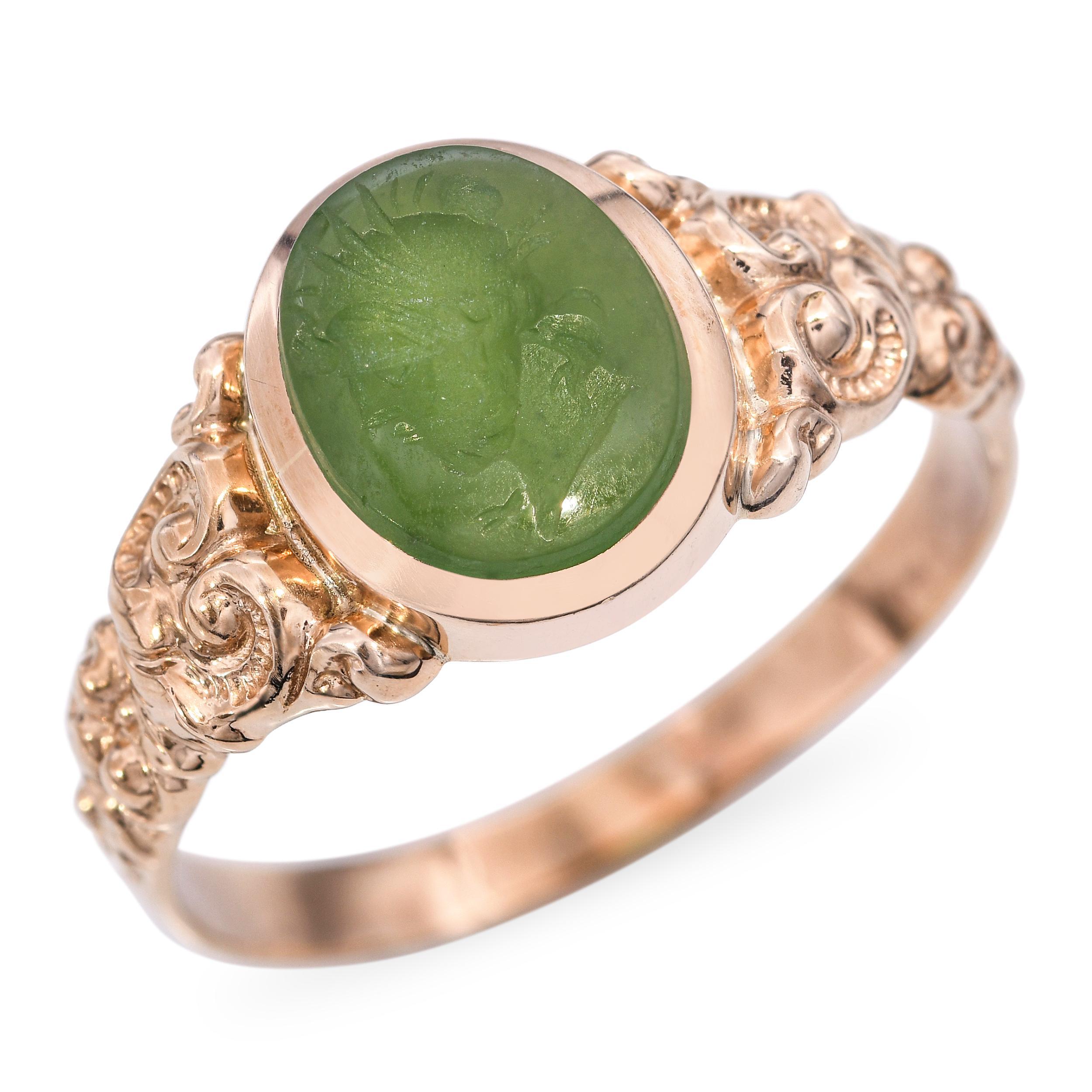 Questo anello antico presenta un'incisione romana scolpita a mano in morbido calcedonio verde, incastonata in un'ornata montatura in oro giallo 10k. L'intricata lavorazione dell'oro aggiunge un fascino antico, incorniciando splendidamente il profilo
