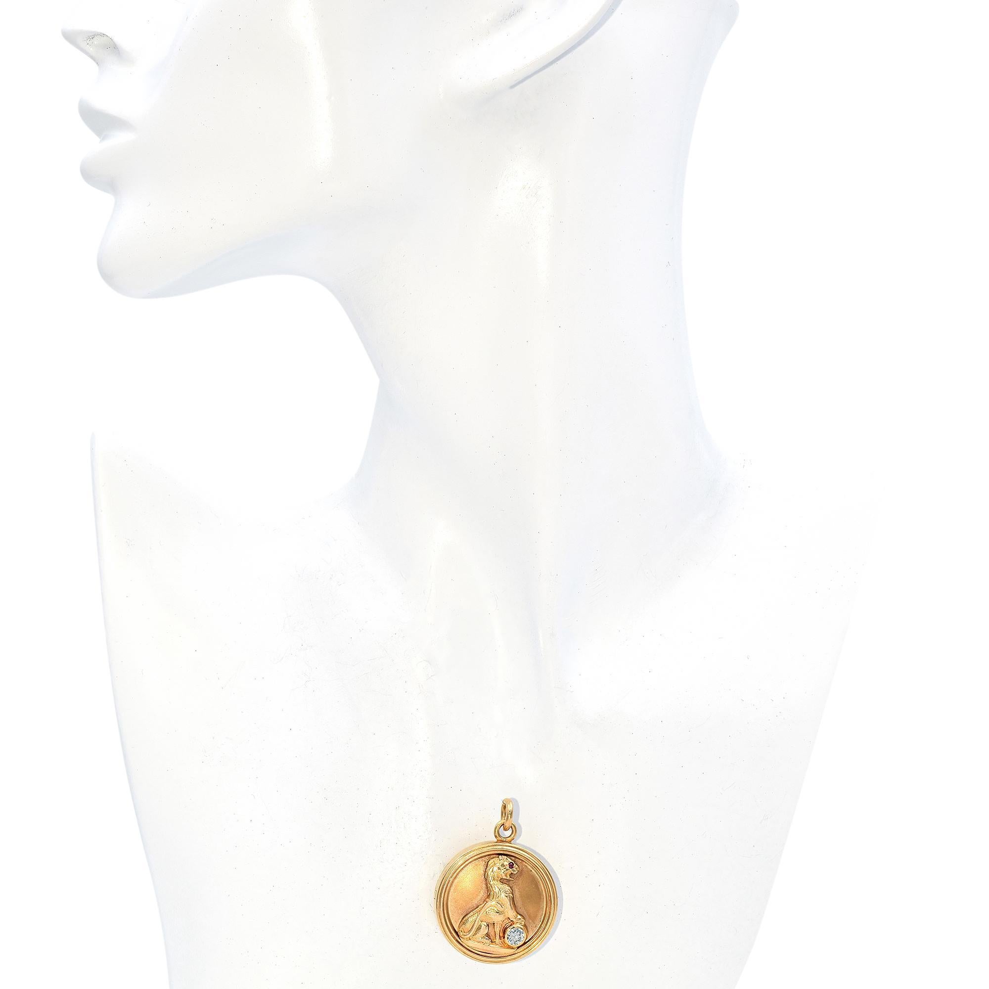 A captivating locket necklace featuring a lion motif in 14k gold. The design showcases a 0.25-carat old European cut diamond, white in color, with VS1 clarity and J color grade. A round cut ruby, red in color, accents the lion's eye. Crafted in the