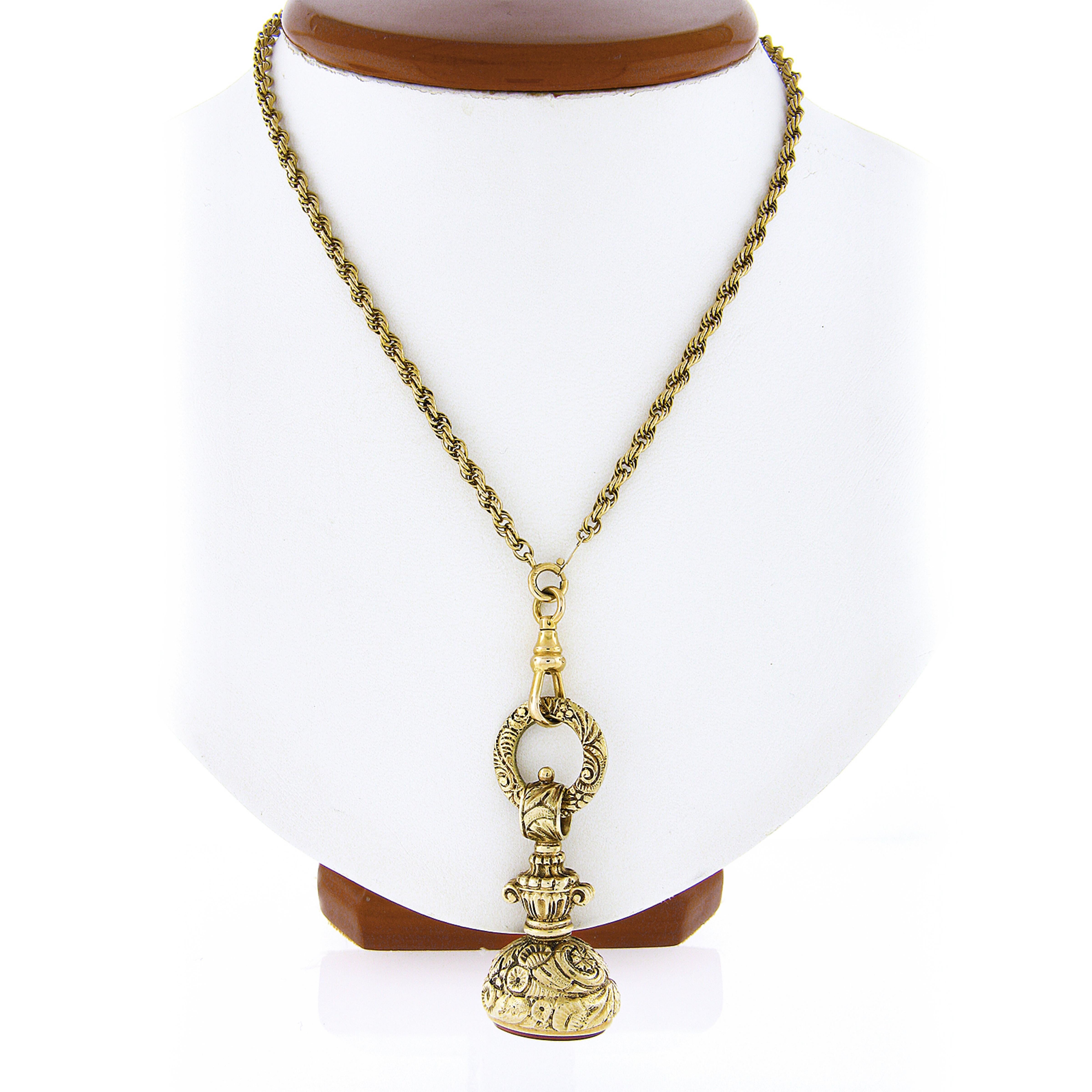 This gorgeous antique fob pendant was crafted from solid 14k yellow gold. It features an oval cut natural carnelian stone bezel set at its base displaying a wonderful rust red color. This exceptional fob is completely covered in very fine and ornate