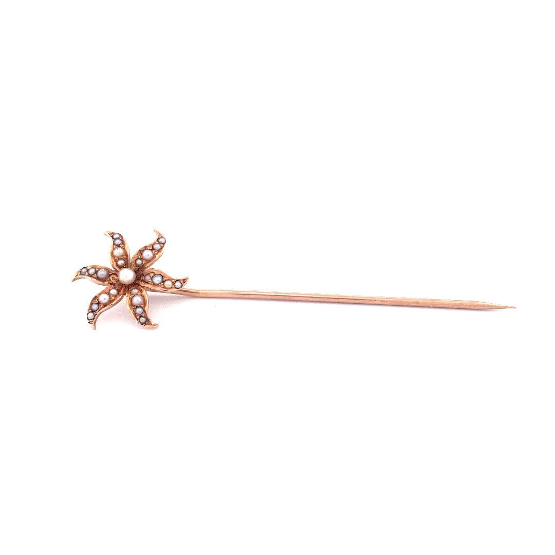 Fai un salto indietro nel tempo con questa squisita spilla con fiore di perle antiche in oro giallo 14k. La spilla presenta un affascinante disegno floreale con sei petali intricati, ciascuno dei quali è ornato da quattro perle brillanti.  Al centro