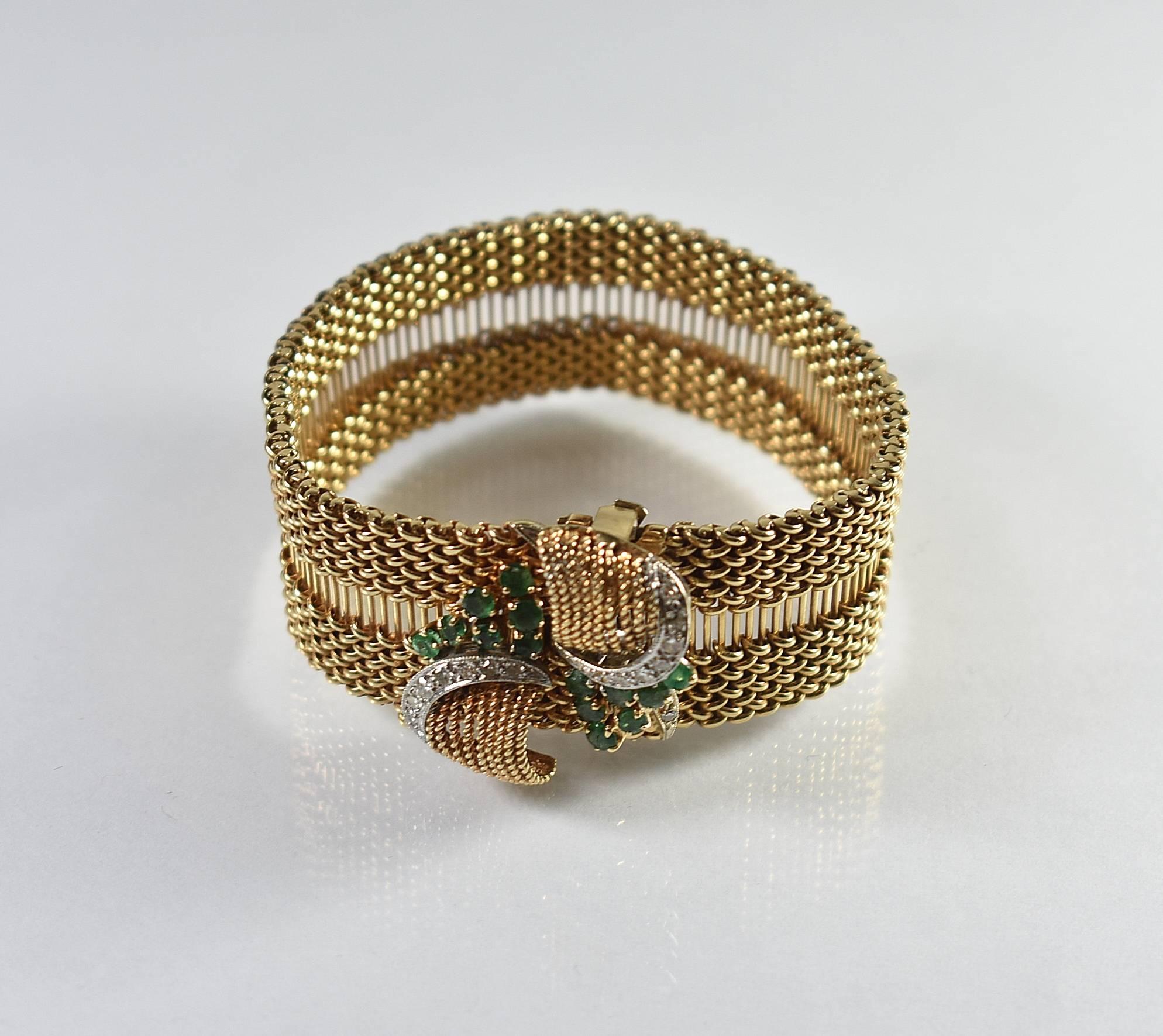 A stunning and 14-karat yellow gold, diamond and emerald bracelet. This beautiful bracelet features a 14-karat mesh link, two hinged clasps with white gold mounts with 16 diamonds and a cluster of 14 emeralds on each clasp. It is 7.5