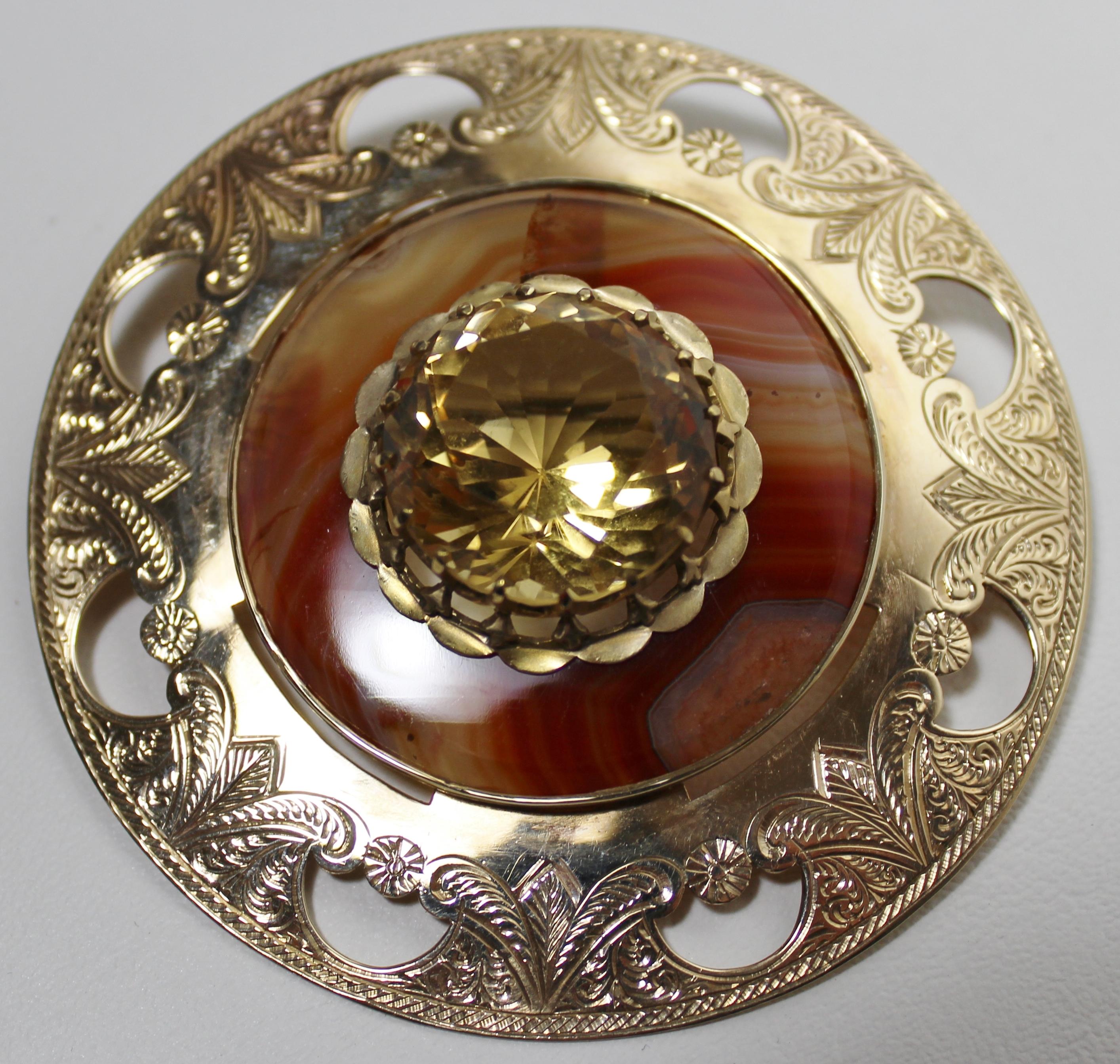 Presumed to be a Victorian brooch with a contemporary assay mark, this artisan made 14- karat yellow gold disc shaped pendant pin is heavily engraved and combined with an agate surround, accent a large cut citrine quartz stone. The intricate