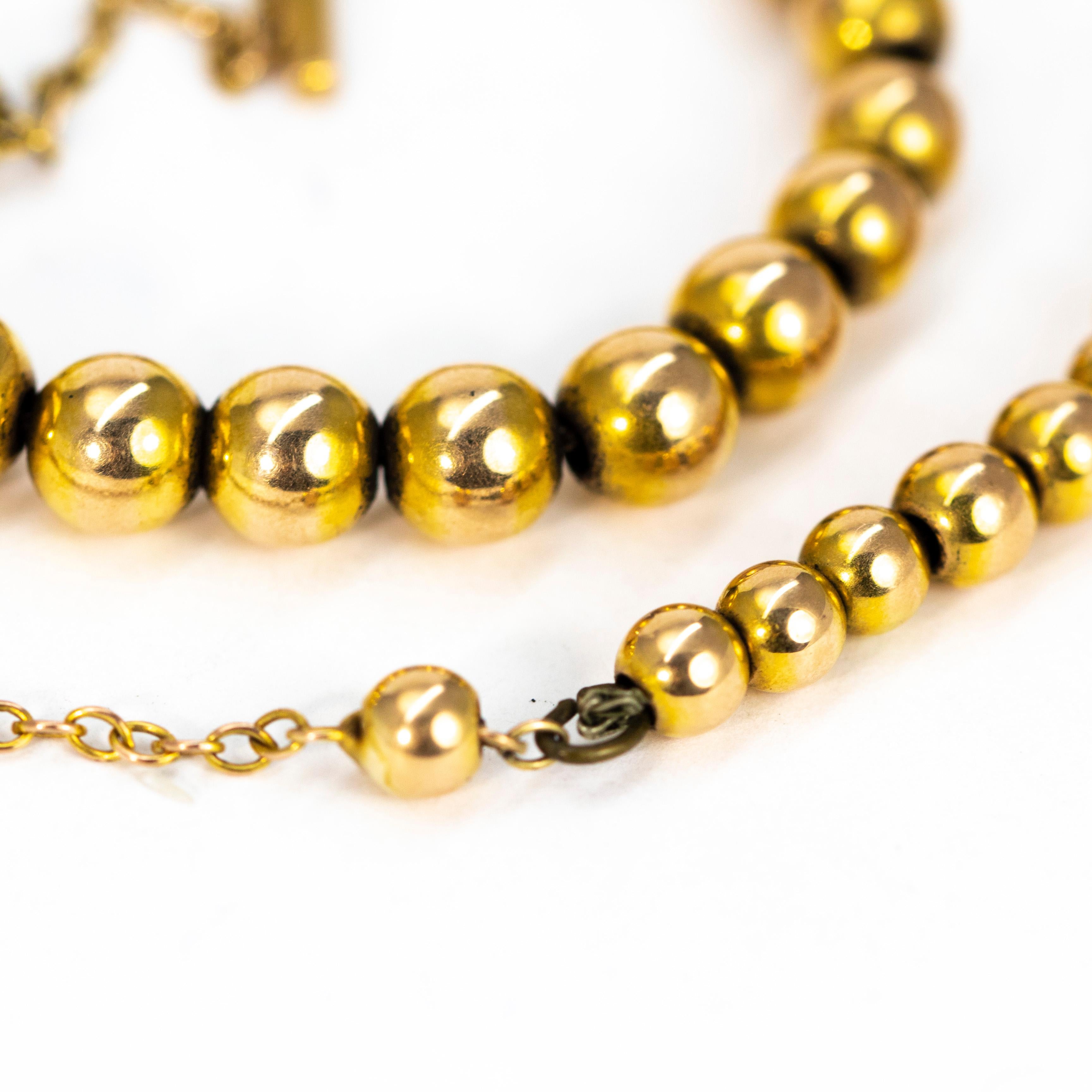 The glossy 15ct gold beads on this necklace slightly graduated in size staring from the largest at the centre and the smallest at the outer edges which then lead into a chain. The necklace is fastened using a classic barrel fastening. 

Largest Bead