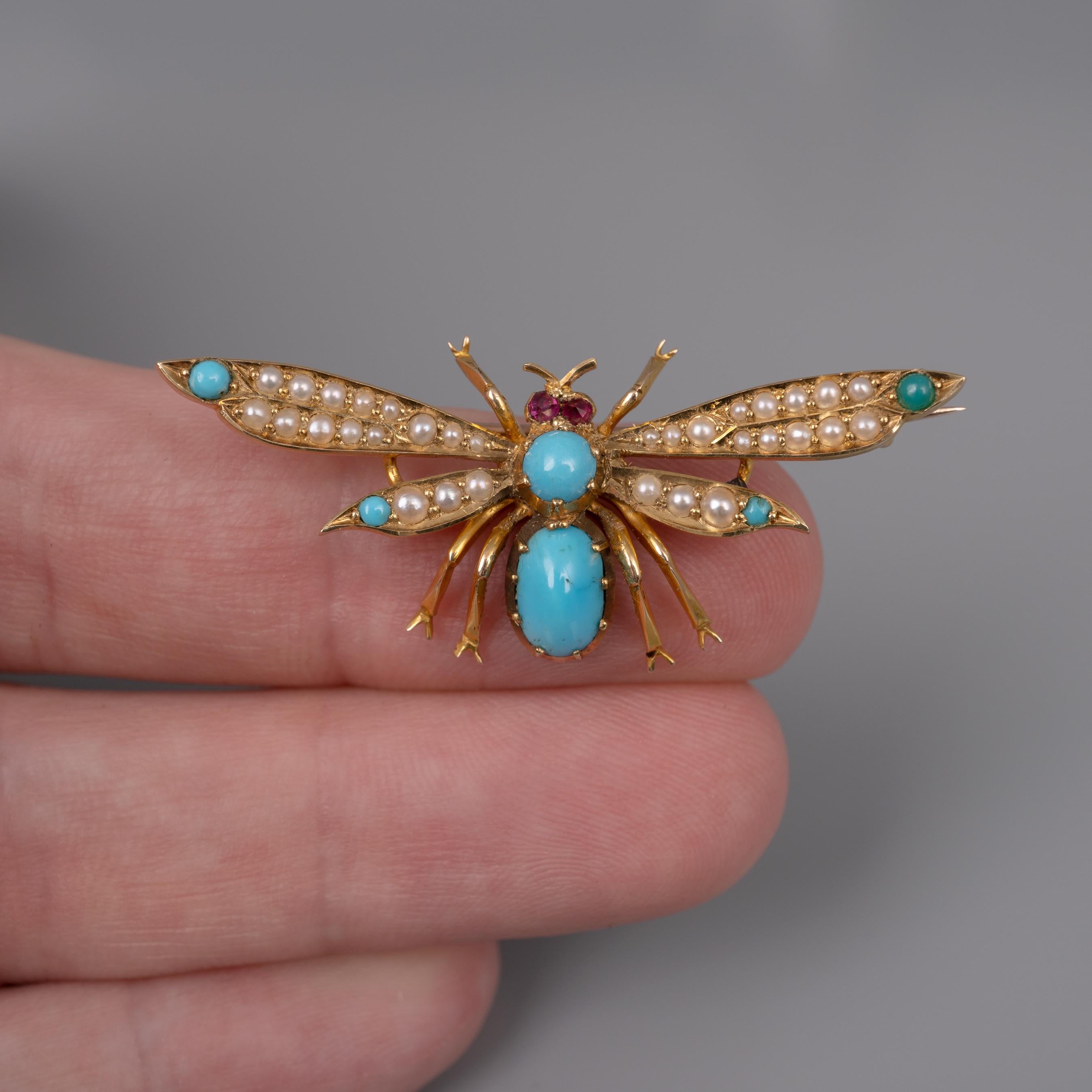 Antique turquoise, pearl and ruby insect brooch crafted in 15 karat yellow gold.

This fabulous double-winged insect brooch is set with natural turquoise to its body and wing tips with seed pearls to the wings and little ruby eyes. It is quite a