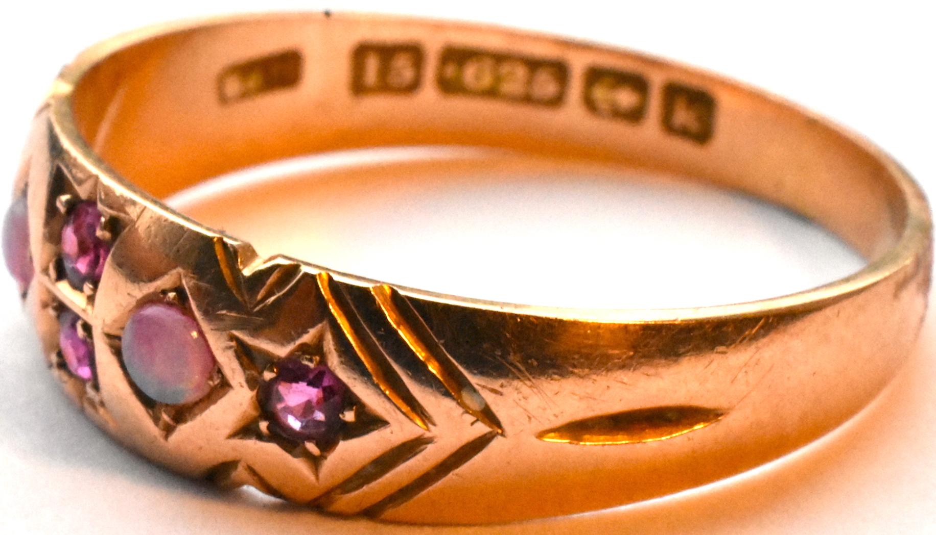 Beautiful antique 15k rose gold gypsy ring with 2 opals set in an incised diamond with 2 rubies at the center and 1 ruby on each side, each ruby set in an incised 5 pointed star (known as a star- setting. Incised lines along each side add interest. 