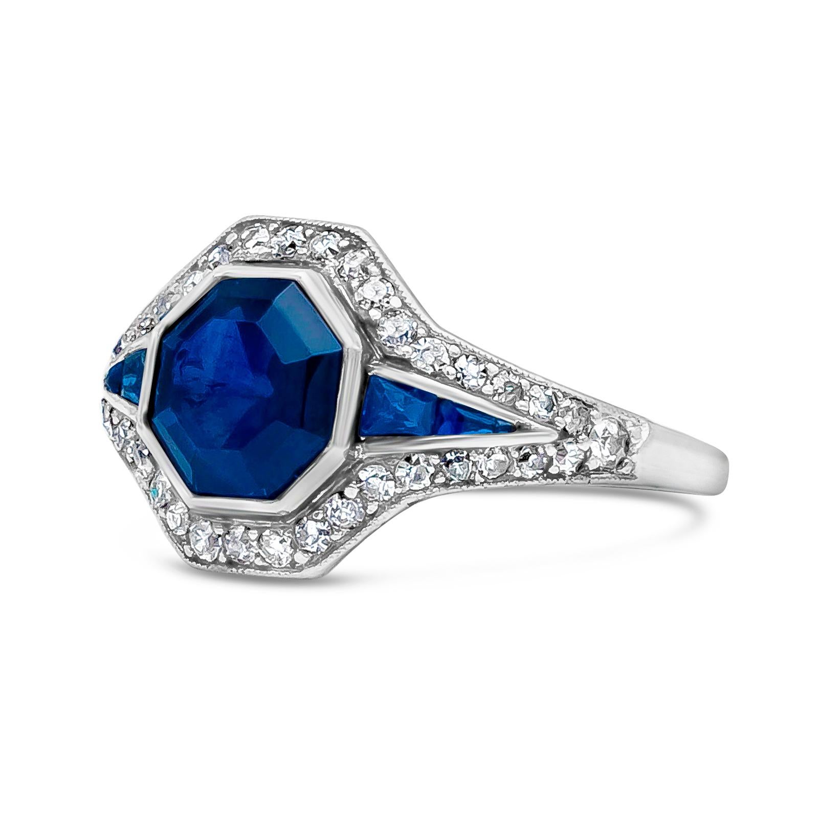 A stunning antique gemstone engagement ring features 1.53 carat asscher cut blue sapphire, flanked by tapered baguette shaped blue sapphires weighing 0.08 carats. Surrounded by antique old european cut diamonds weighing 0.30 carats, G Color and SI