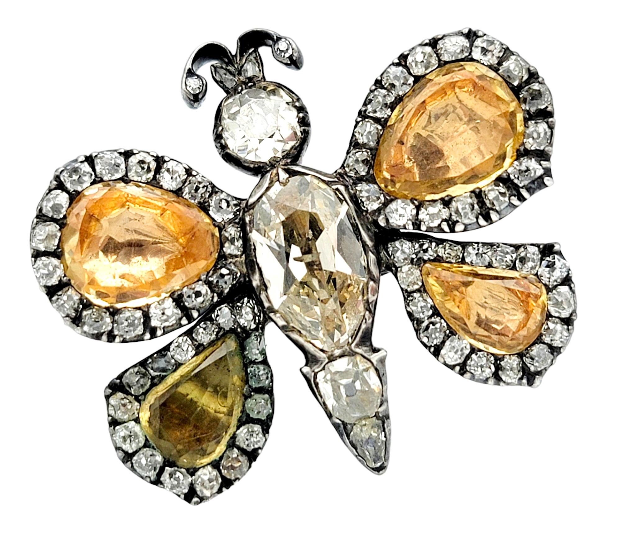 This exquisite vintage butterfly brooch is a stunning testament to elegance and sophistication, crafted in lustrous silver. The focal point of this enchanting piece is the vibrant pear-cut yellowish-orange hues of the topaz that graces the center of