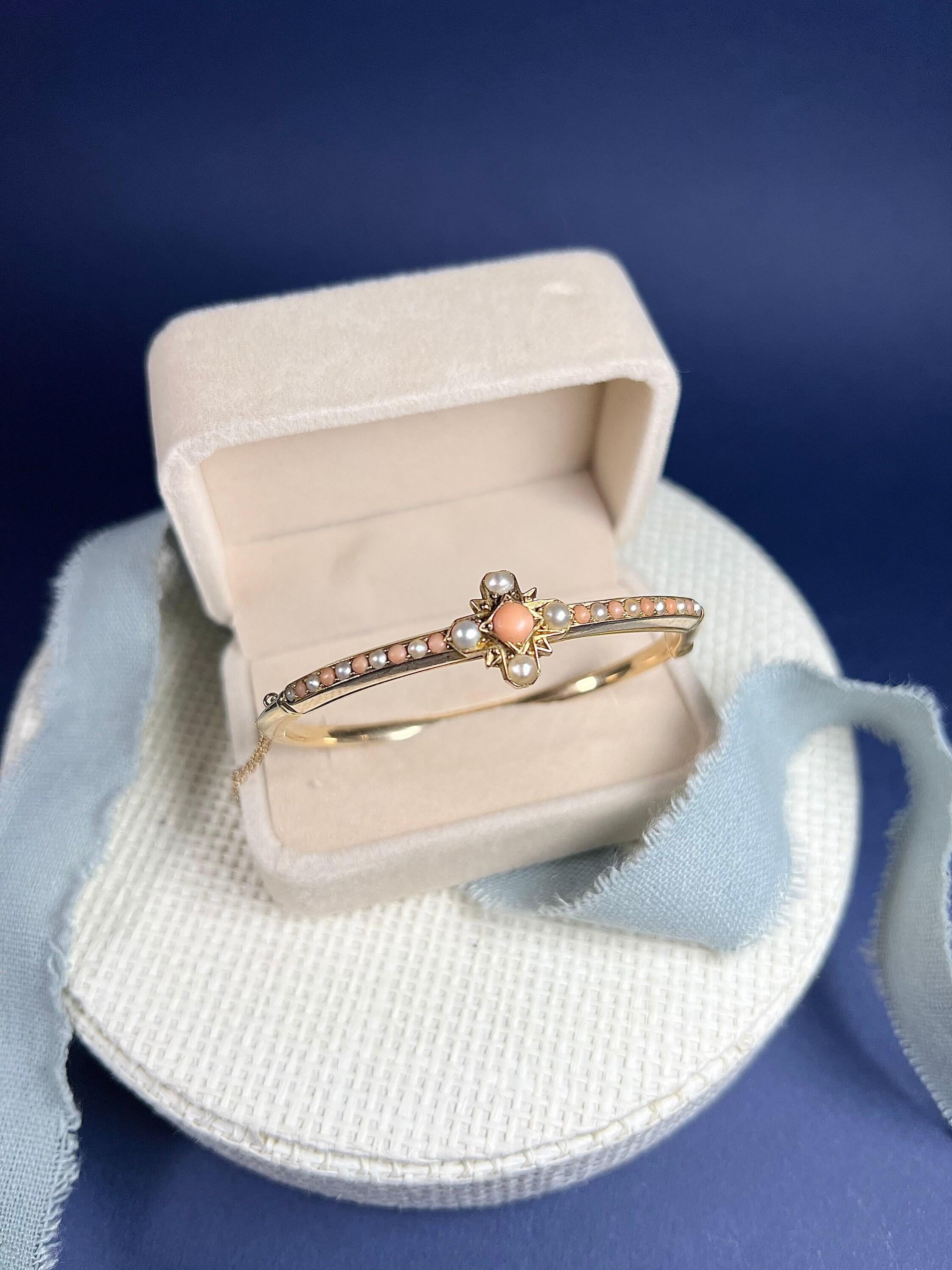 Antique Coral & Pearl Bangle 

15ct Gold Tested 

Circa 1900

Fabulous, Edwardian yellow gold bangle set with round, natural coral & seed pearl stones. The centre forming both a cross & star. Features a knife edge back & secure safety chain.