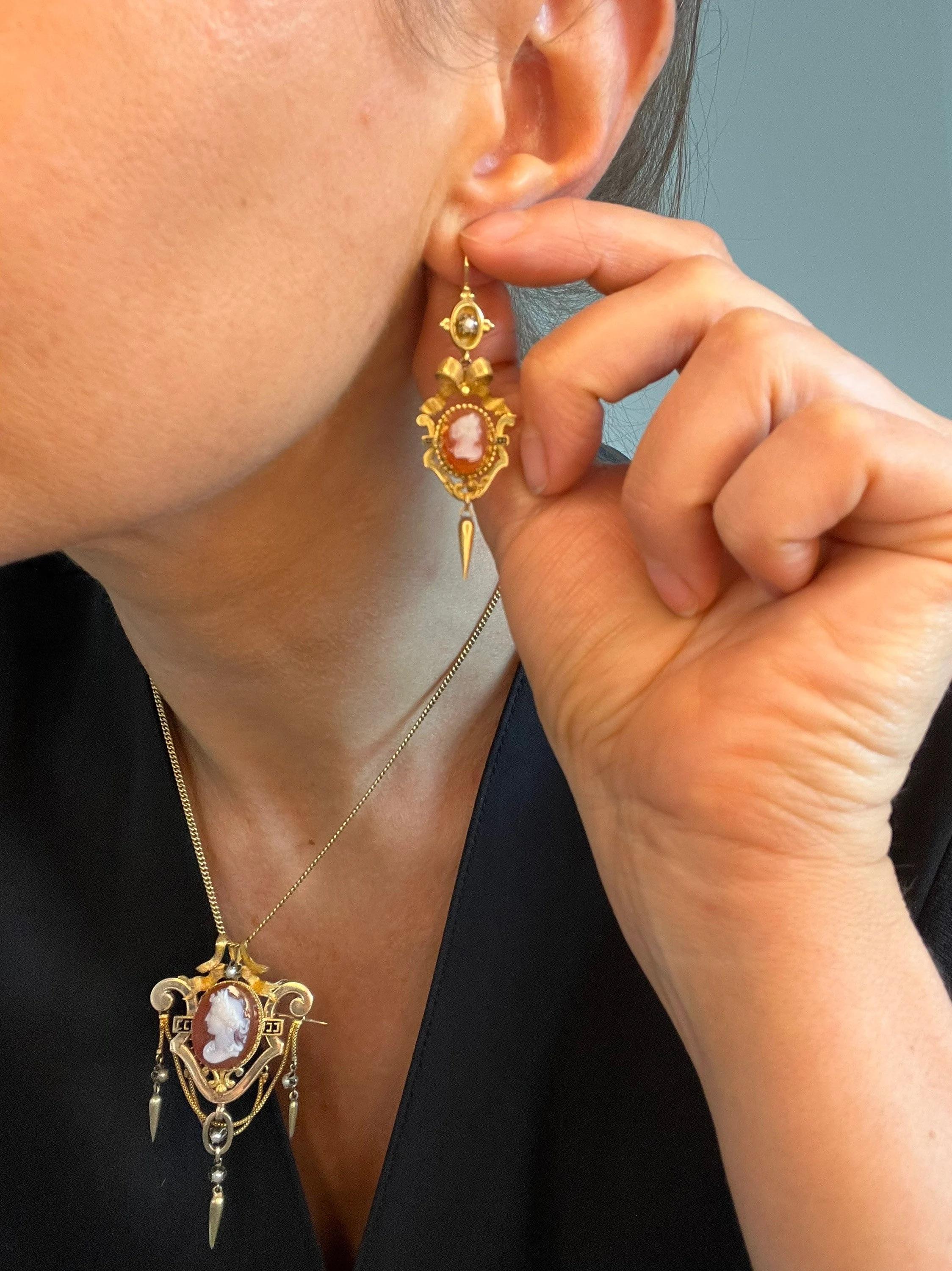 Antique Cameo Earrings 

15ct Gold 

Circa 1870

Gorgeous Victorian, Carnelian Hardstone Cameo Earrings. Beautiful Bow Topped, Drop/Dangle Style Earrings. 
Set with Little Seed Pearls & Torpedo Drops. 
Beautifully Decorated with Gold Scrolls & Black