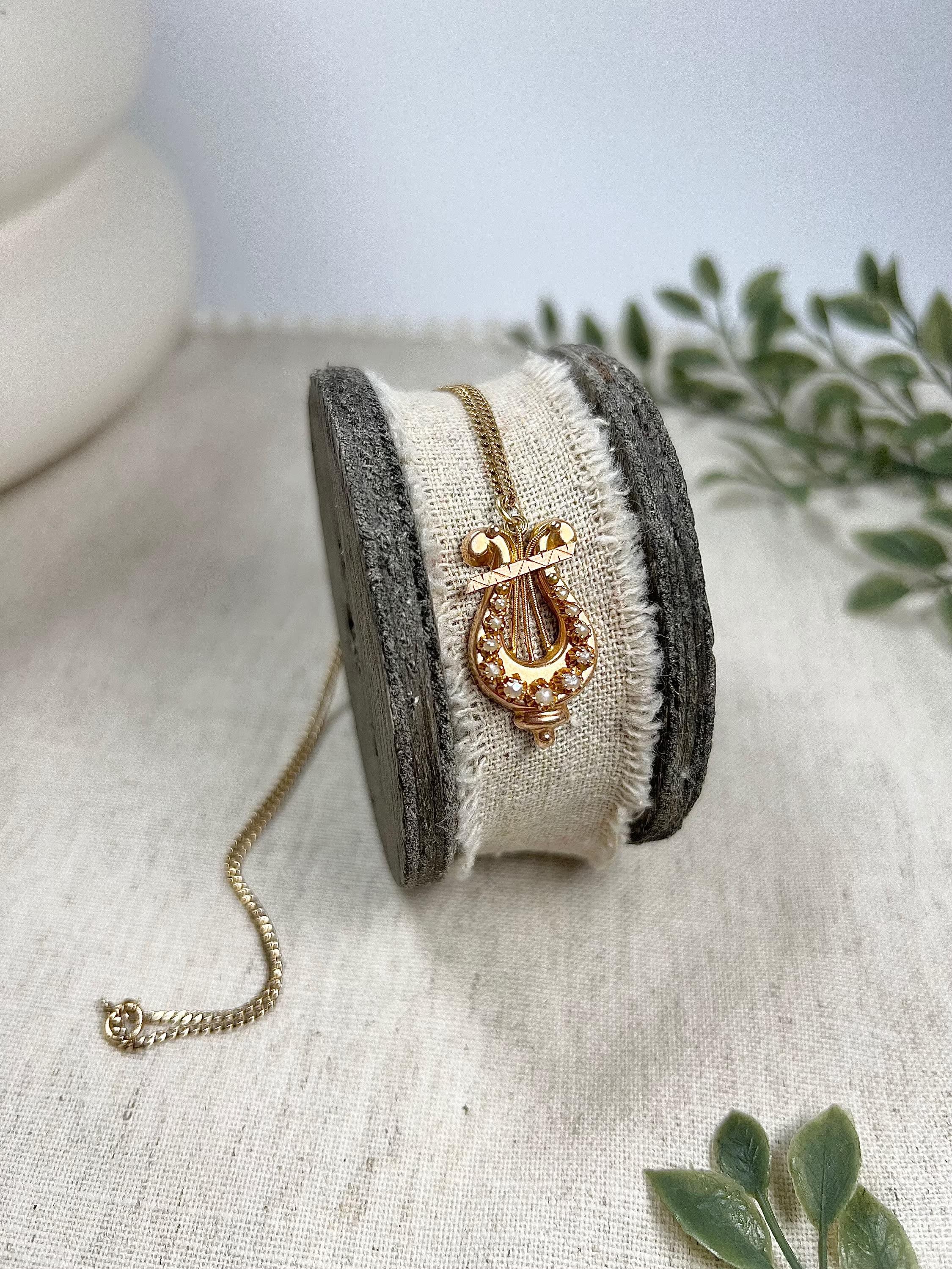Antique Harp Necklace 

15ct Gold Tested

Circa 1880

Beautiful, Victorian harp shaped, pendant necklace. Set with pretty, natural seed pearls & fabulous gold work. 
The pendant is suspended from a modern 15ct gold, curb link chain. 

Pendant