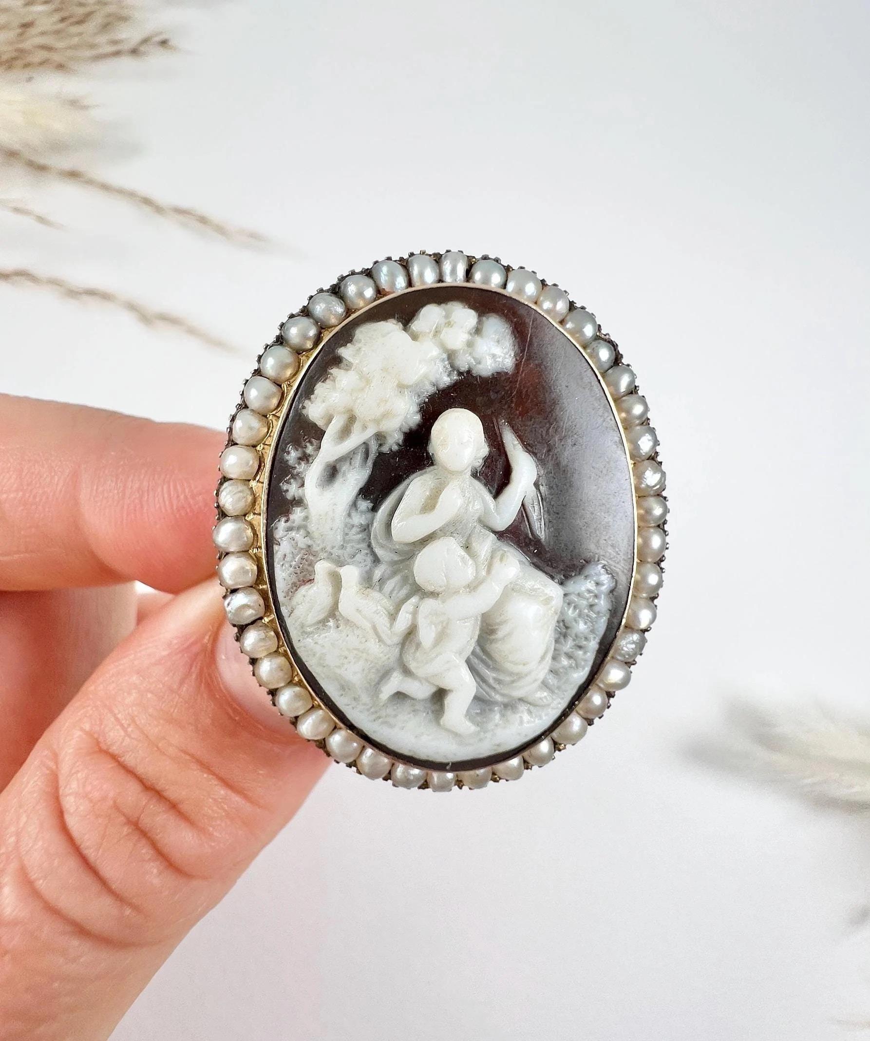 Broche Camée Antique

Or 15ct estampillé 

Circa 1875

Cette exquise broche victorienne en or 15ct présente un captivant portrait en coquillage représentant une scène sereine avec un arbre, deux colombes, une femme et un petit chérubin. La broche au