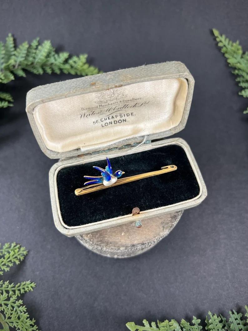 Antique Bird Brooch

15ct Gold Stamped

Circa 1900

This exquisite Edwardian bar brooch is a true masterpiece. Crafted from 15ct gold, it features a lovely bird design with a natural pearl body and fabulous blue enamel head, tail and wings. The