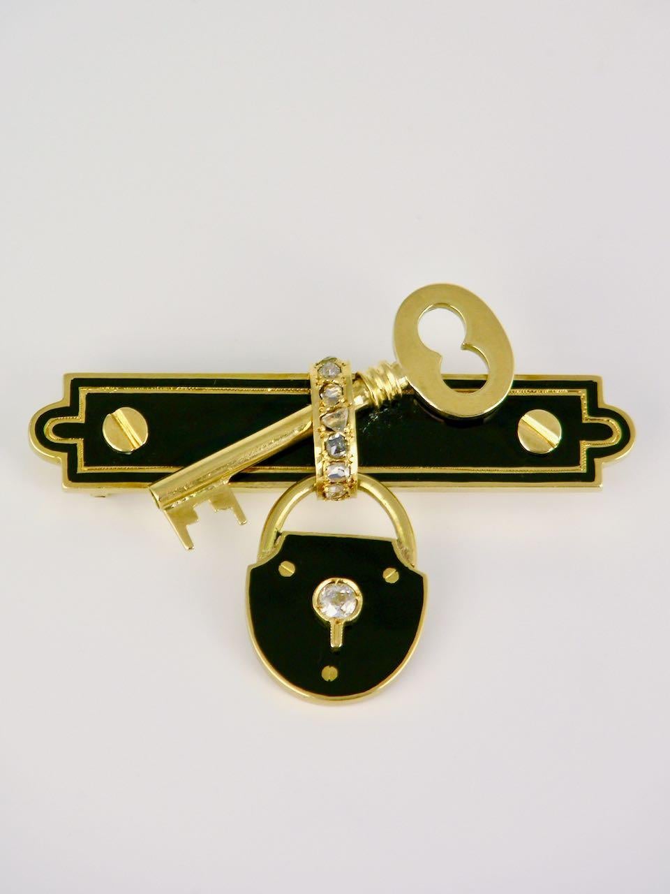 A 15k yellow gold black enamel diamond lock and key brooch - a late 19th century pin of a unique design of a padlock decorated in black enamel with an old cut diamond set within the key hole and suspended below a black enamel bar brooch with screw