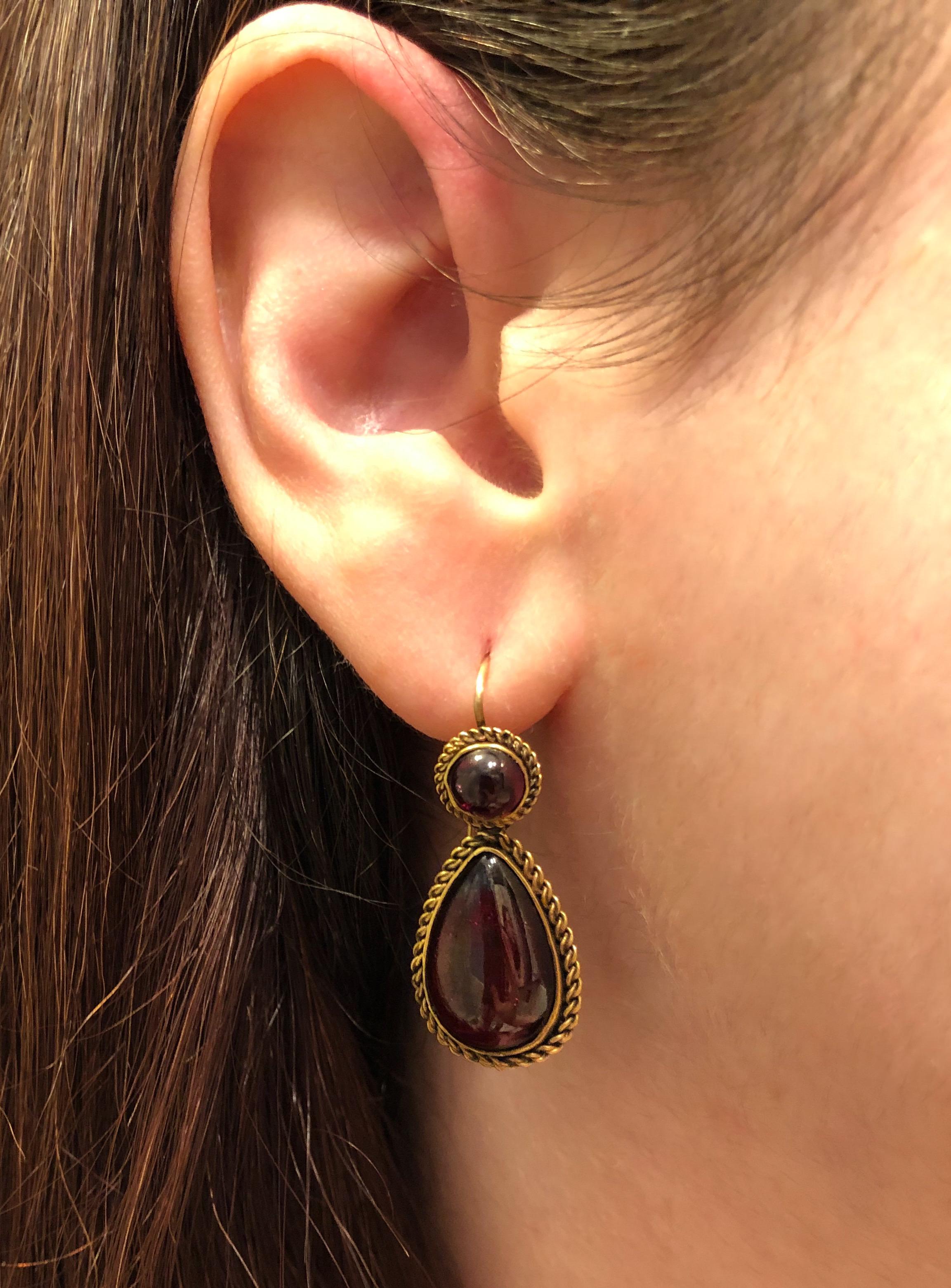 Cabochon garnets are set in 15 karat yellow gold closed back earrings with rope trimmed edges. Length 1-3/8 inches, width 9/16 inch.
