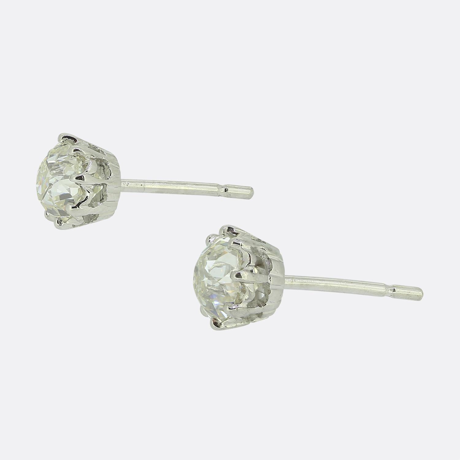 Here we have a refined pair of diamond stud earrings. Each identical piece showcases a classic design, featuring a single round faceted old mine cut diamond set in a secure platinum setting, enhancing their brilliance. The intricate prong detailing