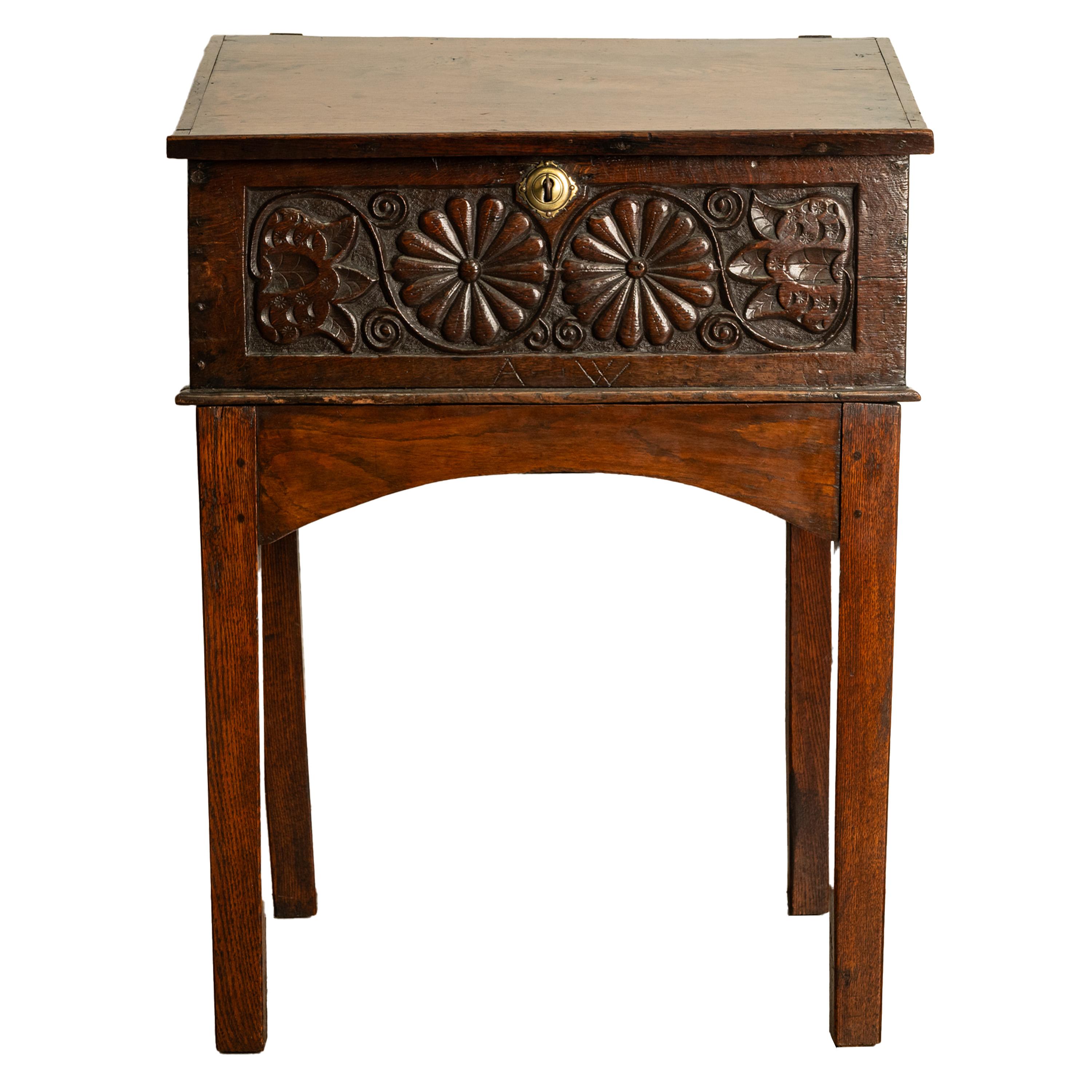 A good antique Charles II carved oak bible box, desk on stand, circa 1680.
The box and stand in two sections, the bible box having a hinged lid with a ledged sloped writing surface, locking with a key and brass escutcheon. The front of the box is