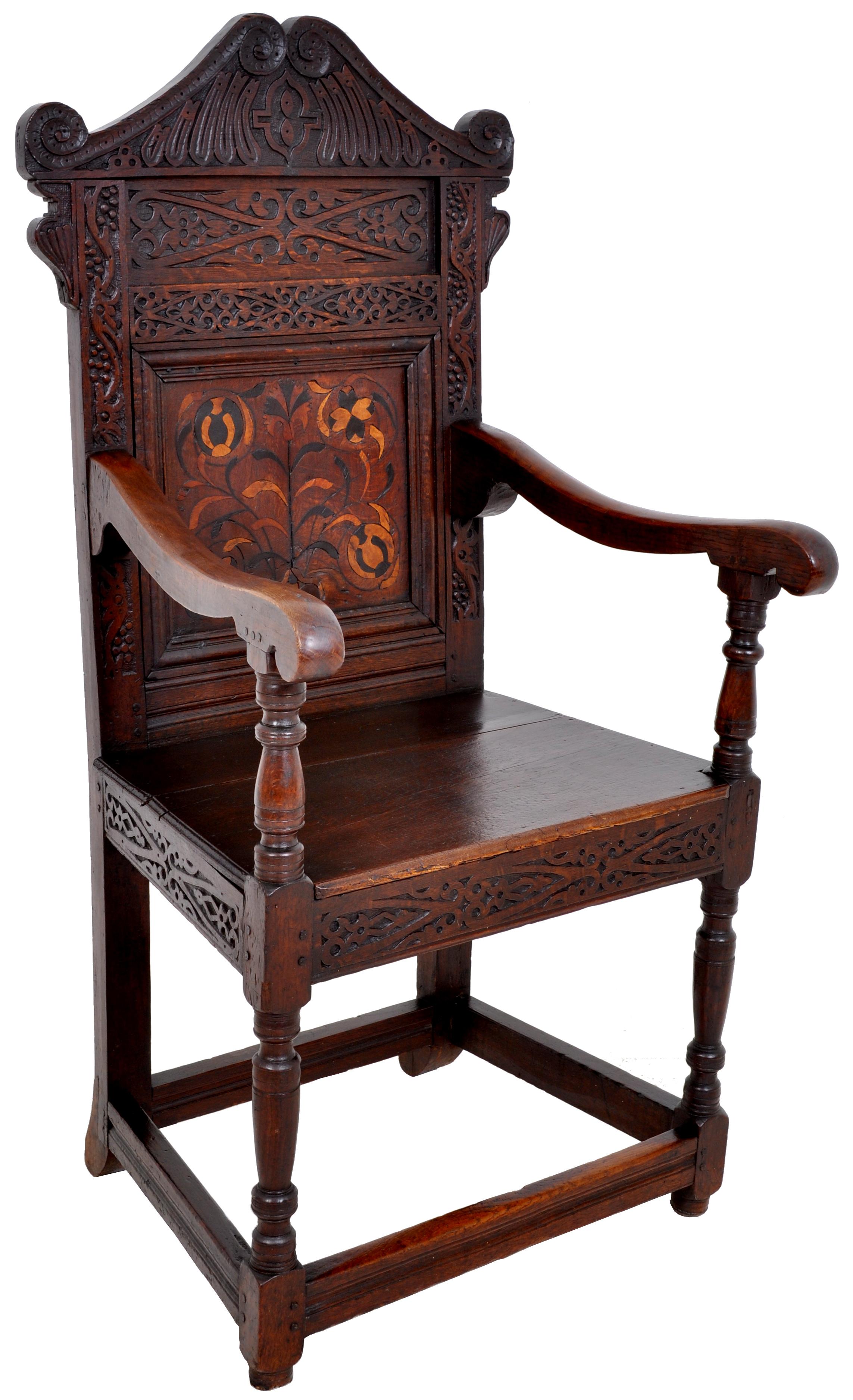 A rare antique inlaid oak carved Wainscot chair, Charles II period, circa 1670. The chair having a carved top rail pediment, the back carved with fruiting vines and geometric devices. To the center of the chair back is an inlaid floral panel of