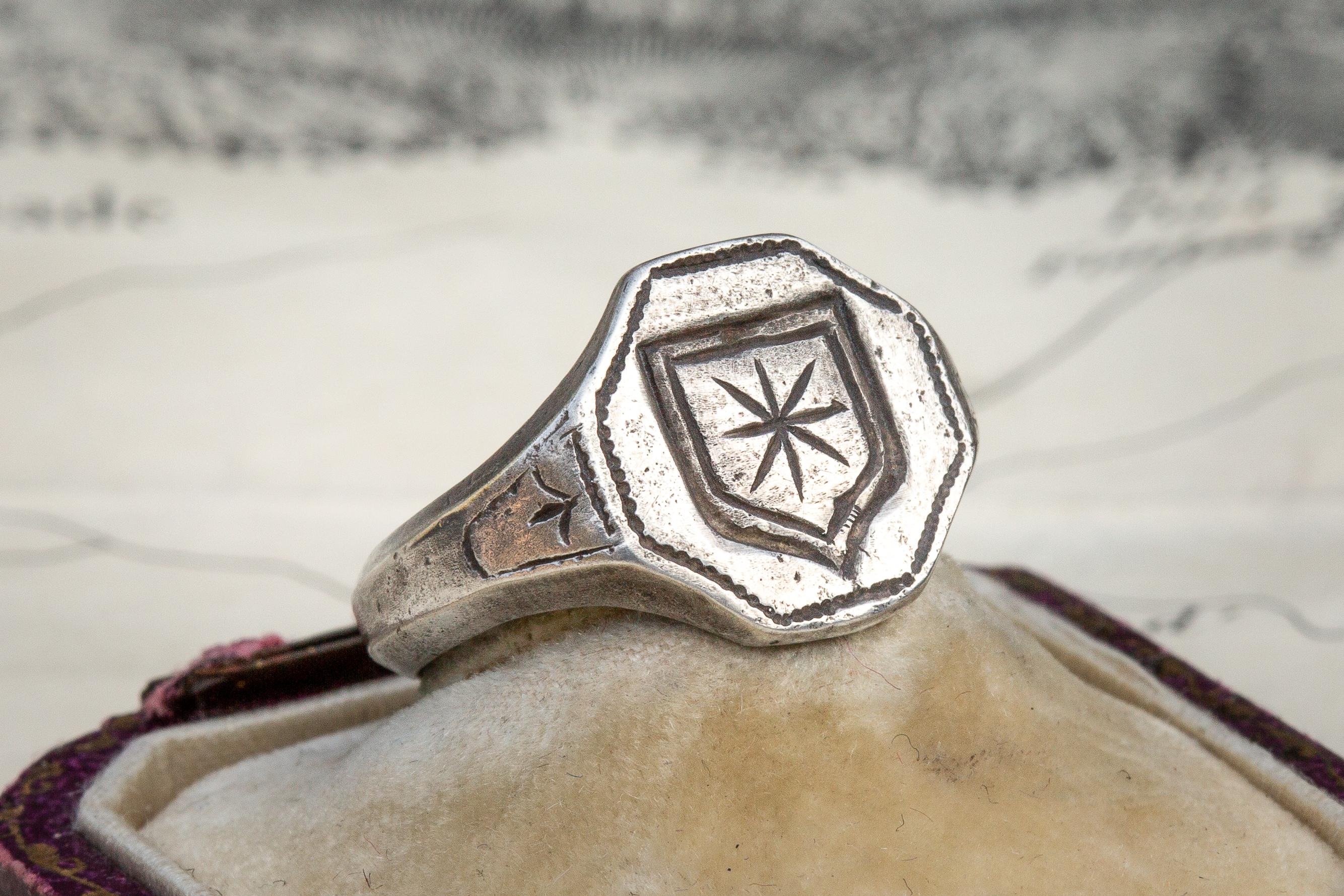 This rare heraldic silver intaglio signet ring dates from the late 17th century and originates from Western Europe. The flat, octagonal bezel is engraved with a noble family coat of arms depicting an eight pointed star. The silver ring is cast in