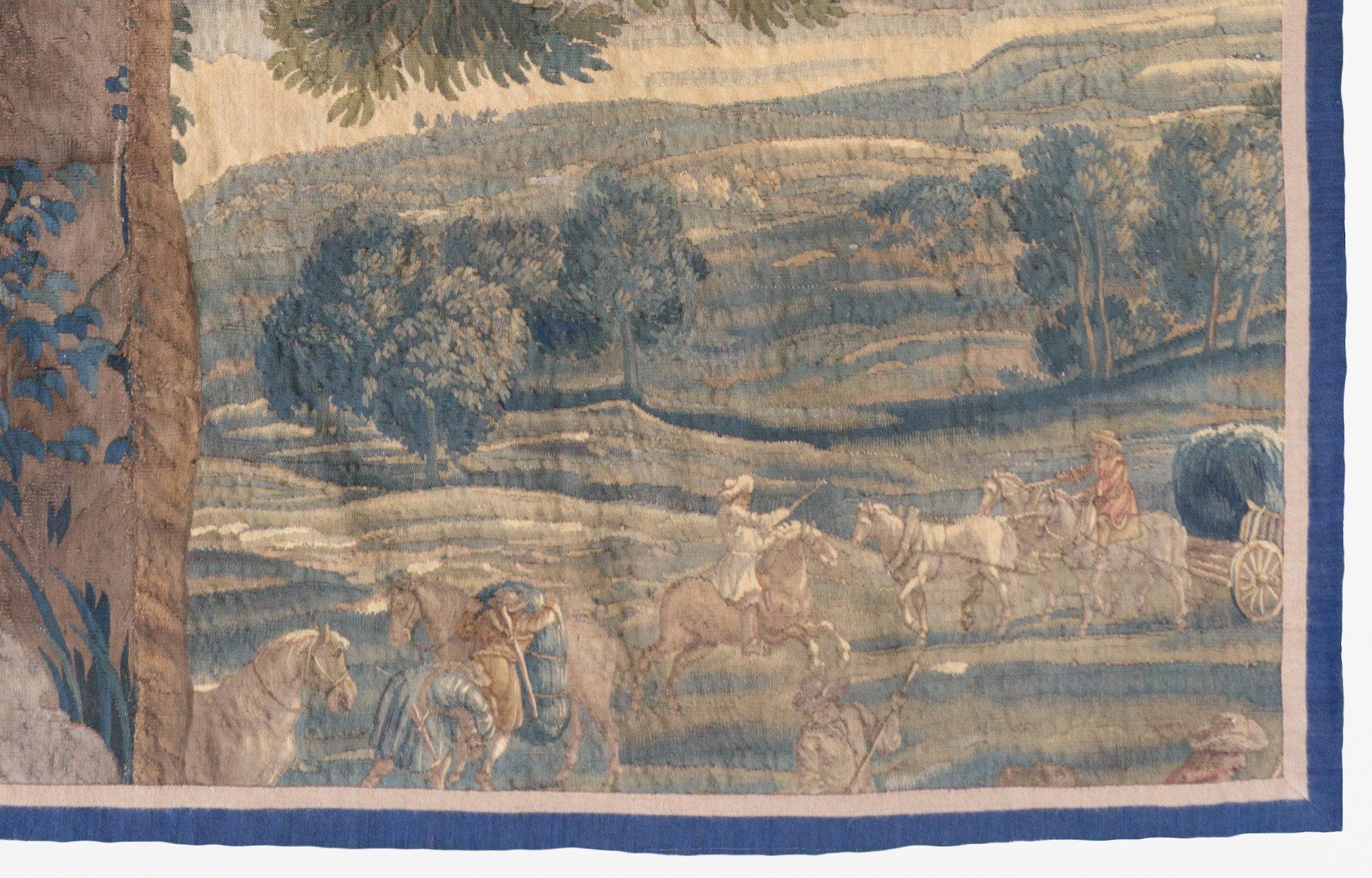 Antique 17th century Flemish verdure landscape tapestry depicting a lovely countryside with lush trees and vegetation, rolling hills, figures, horses and covered wagons. Please note that it does not have its original border and has been reduced from