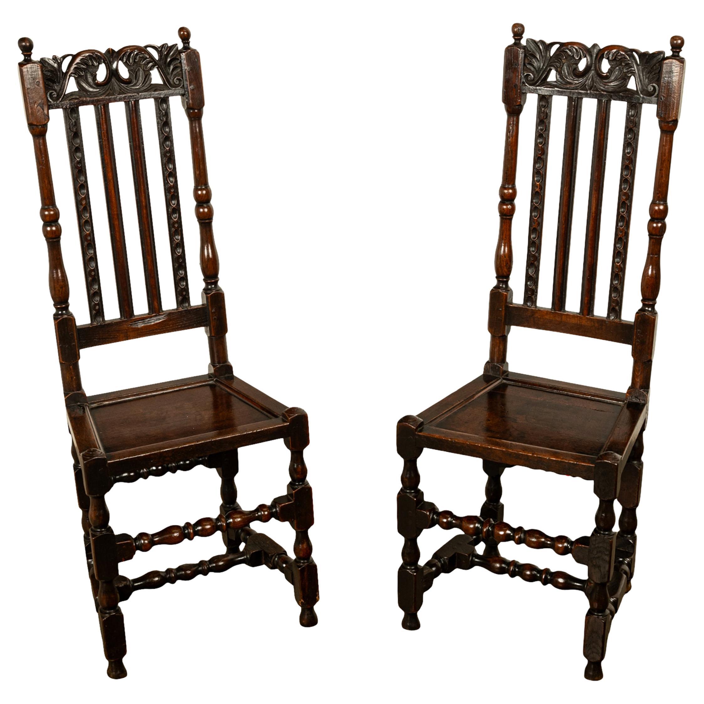 A very good pair of antique William & Mary joined oak side chairs, circa 1690
Each back with a pair of turned ball finials above a carved  pierced crest rail, below are four narrow moulded & carved slats mortised between the scroll-profiled cresting