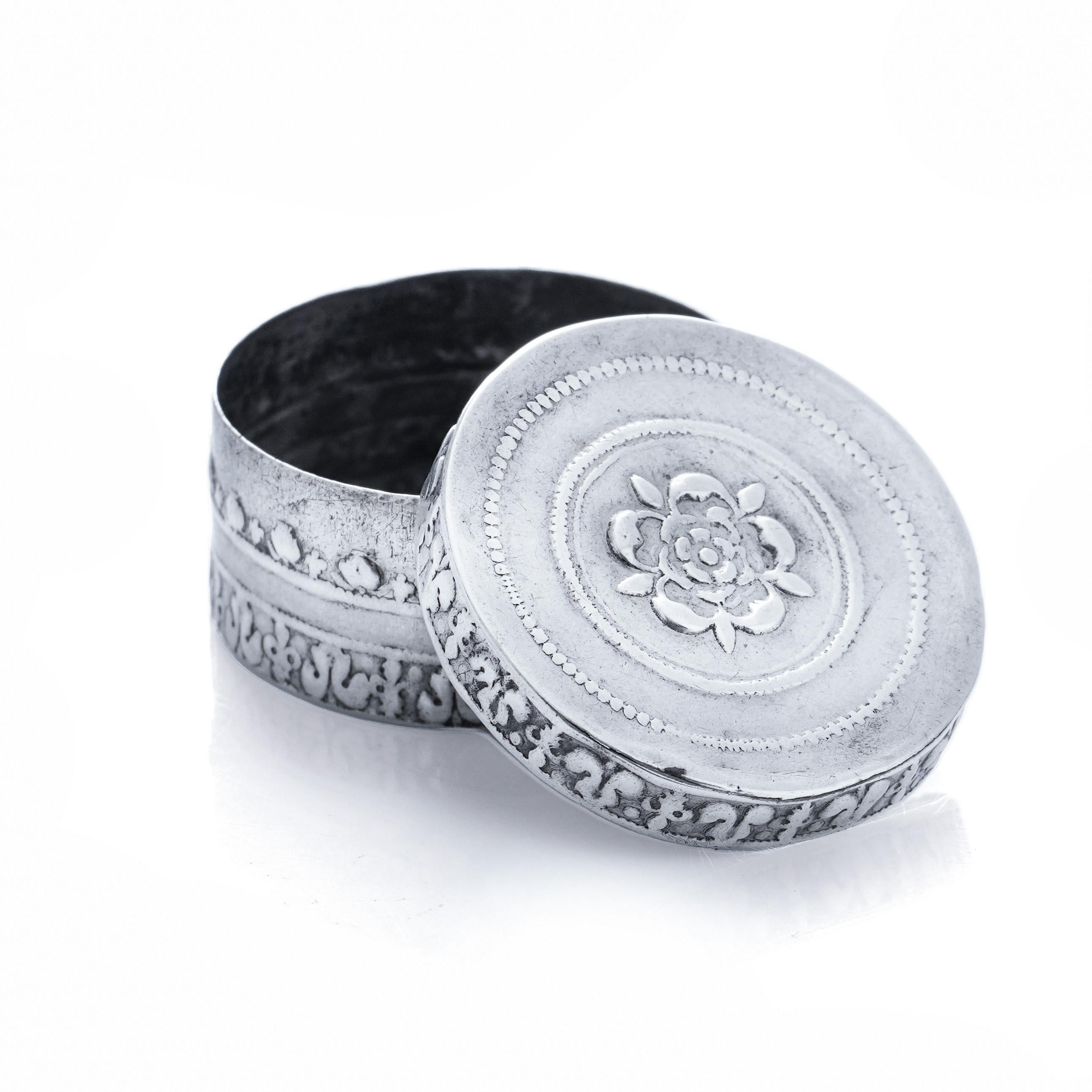 An antique round patch box, crafted in sterling silver during the 17th century, is potentially from the era of Charles II. The silver circular box and cover showcase embossing featuring a Tudor Rose within a bordered design. The interior is
