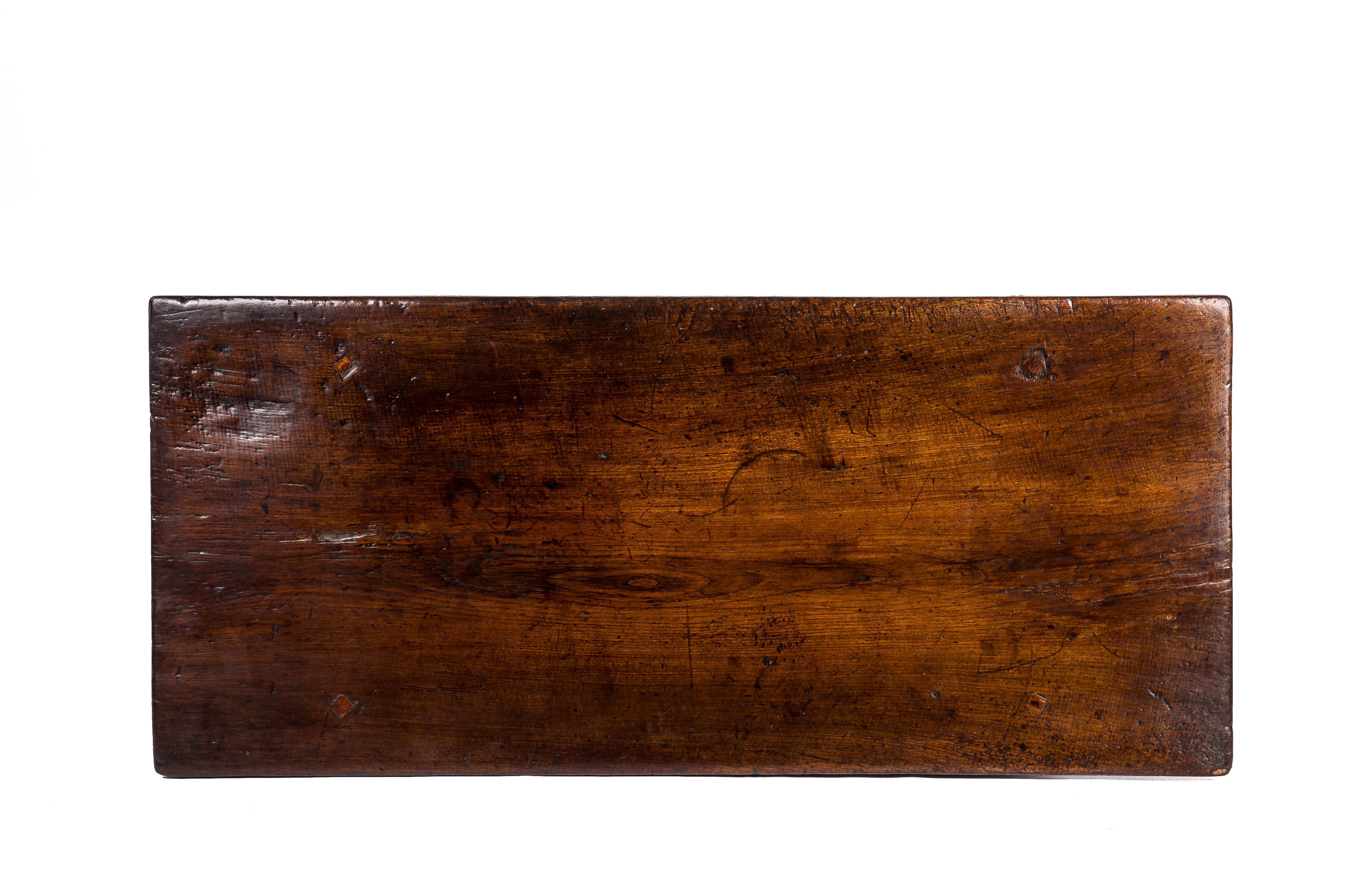 This fantastic coffee table was completely made in solid chestnut and originates in Spain circa 1650. Its large top is made from a single board of 1.2 inches thick solid chestnut with a beautiful grain pattern. The top shows the marks of over 350