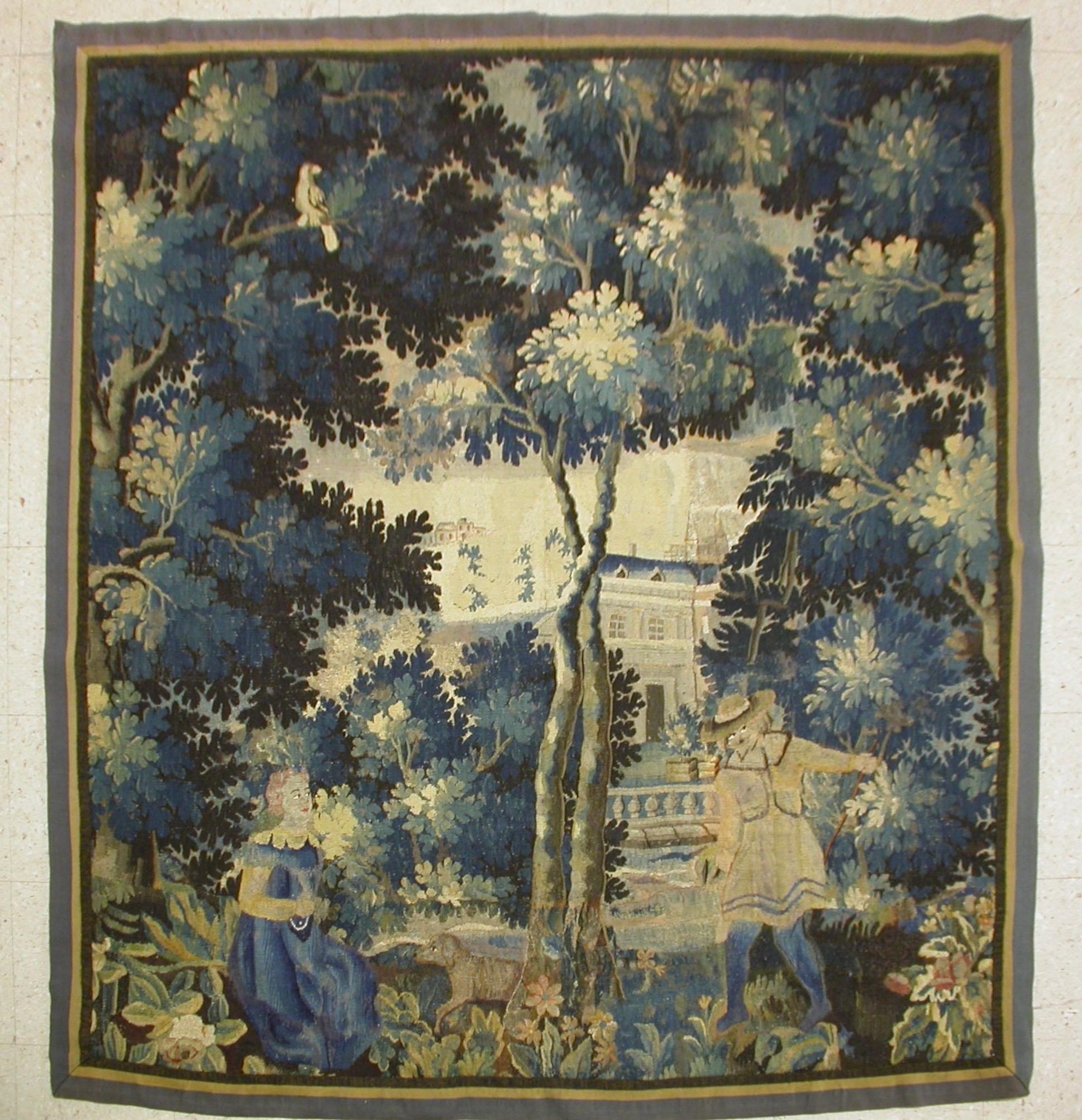 This is a gorgeous antique square 17th Century flemish Verdure landscape tapestry with two slight figures in a beautiful and rich summer scene of a countryside with lush trees and vegetation and homes in the distance. 

The piece measures 6.3 x 6.9