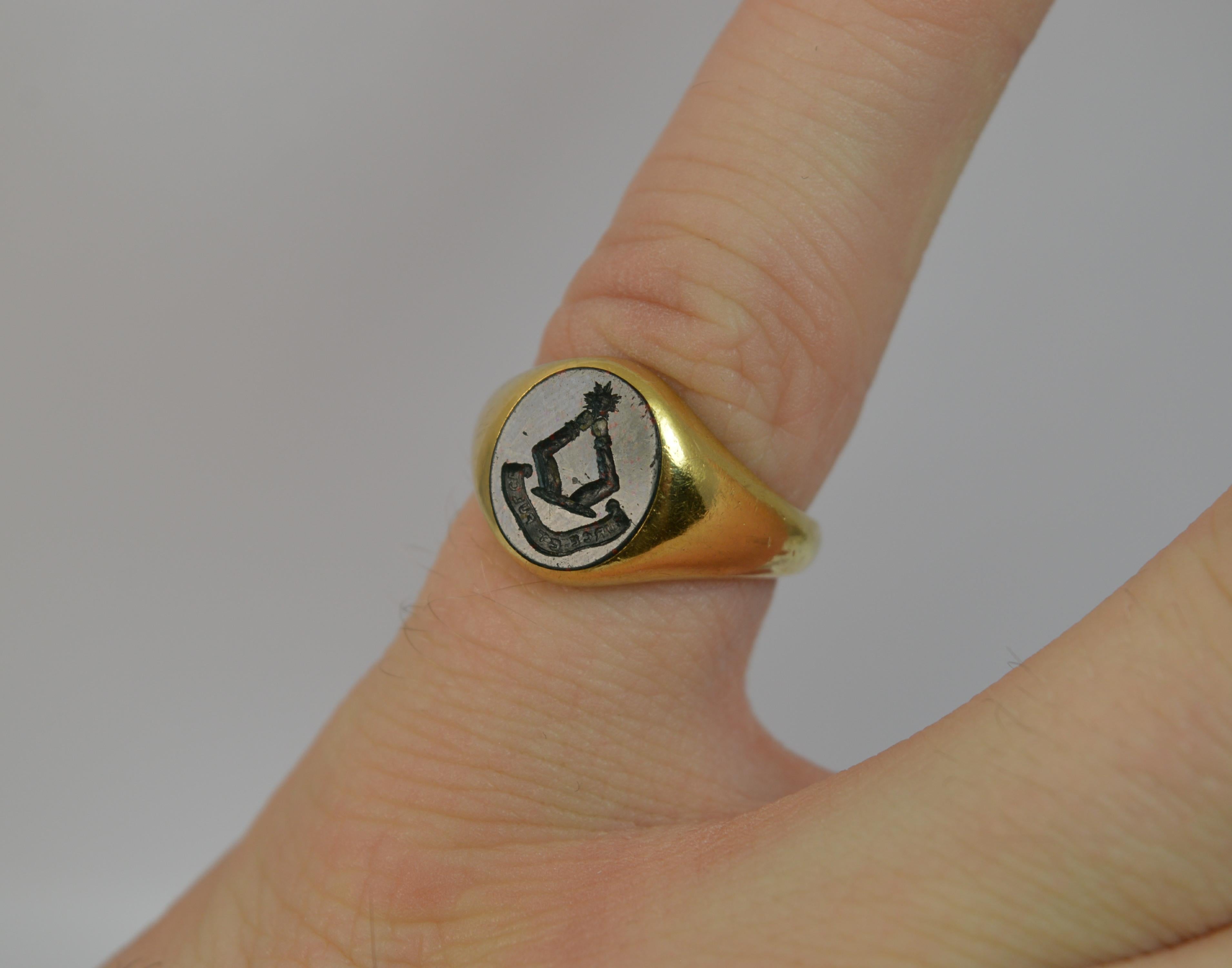 A stunning 18 carat gold and bloodstone pinky ring.
SIZE ; H UK, 4 US
Solid 18 carat yellow gold throughout.

Set with a single oval bloodstone panel with intaglio of two arms reaching up to hold a sun and below a moto which seems to read Surce Et
