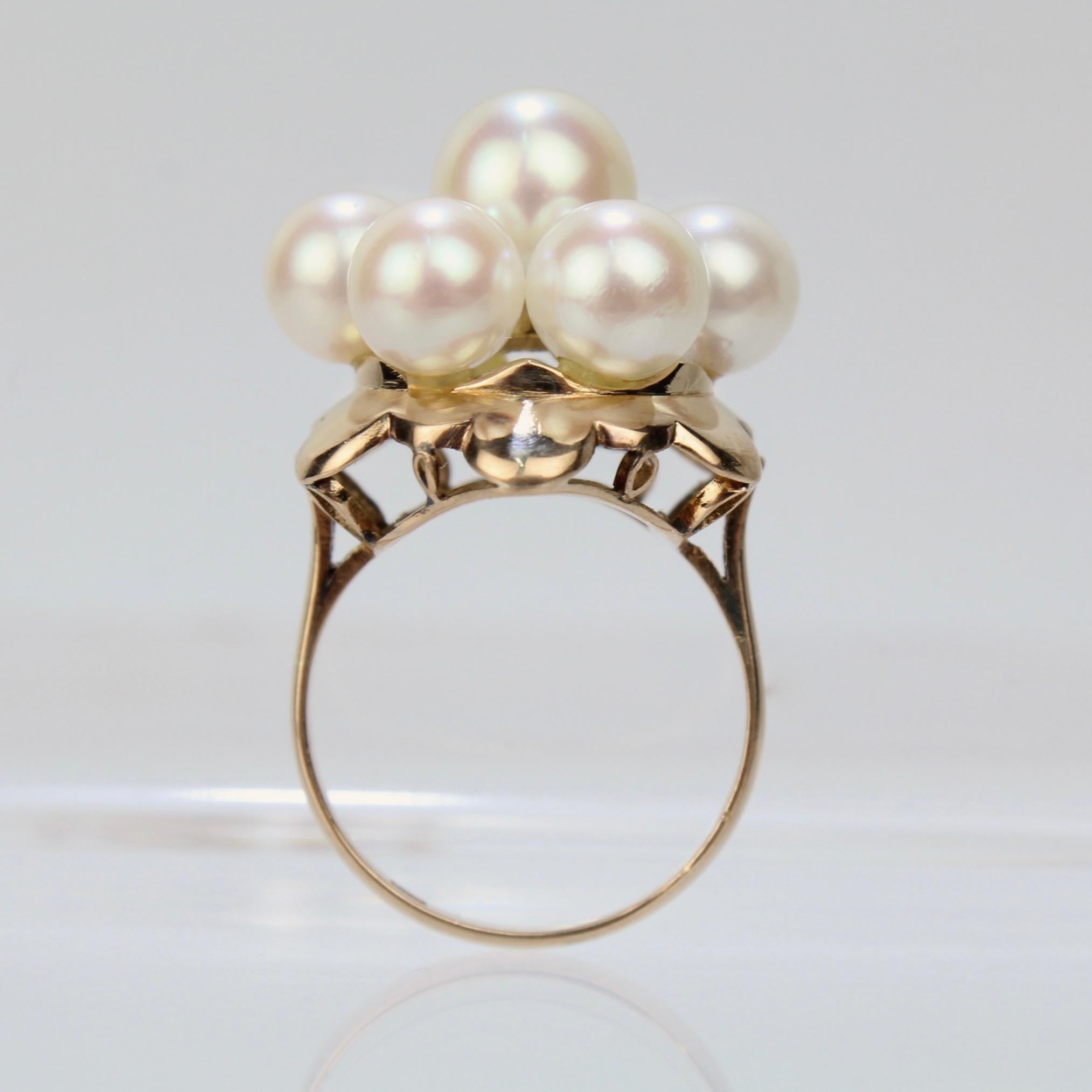 A fine gold and pearl cluster Mid-Century cocktail ring.

The ring has an 18k gold petal shaped setting that is supported by a gallery with open work and is set with fine round, white pearls. The largest pearl measures approximately 8 mm in
