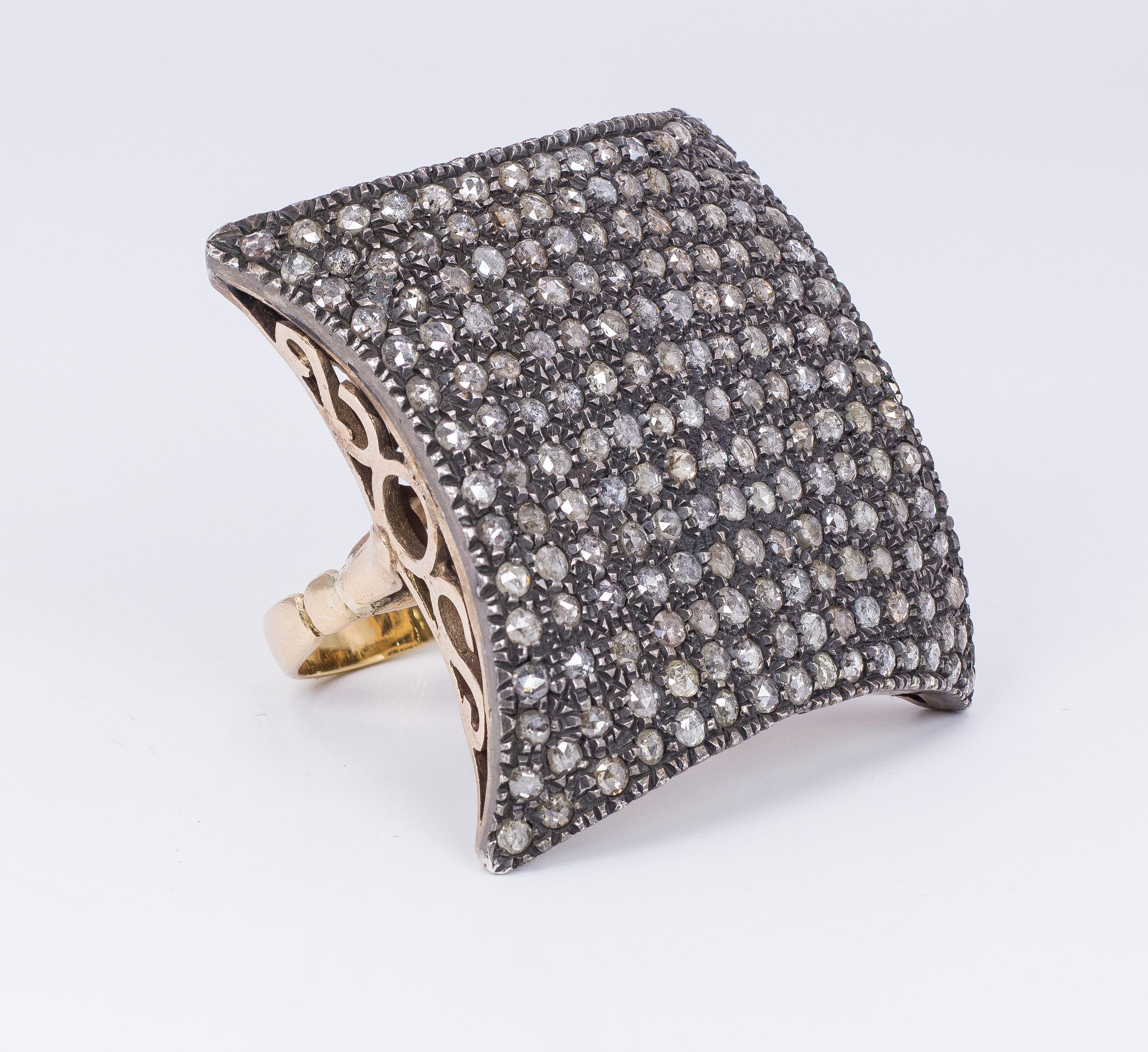 This very particular and incredible antique ring, dating from the 1940s, has a square shape, studded with rose cut diamonds. 
The head of the ring is held up by a stunning worked mounting, with geometrical and exaggerated openworks throughout. 
The