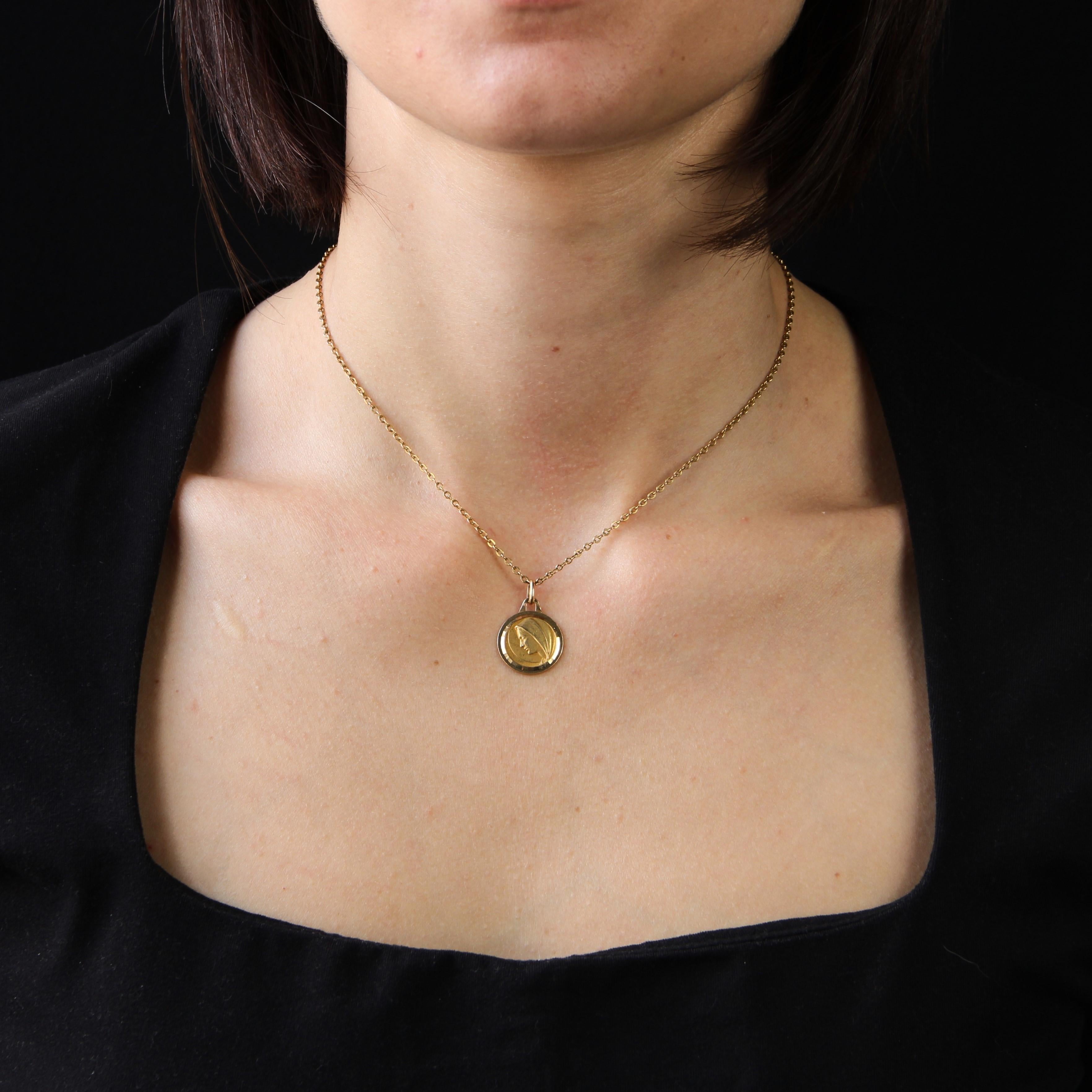 Medal in 18 karat yellow gold, eagle head hallmark.
This religious pendant features the profile of the Virgin Mary surrounded by two borders of faceted yellow gold.
The back is engraved: 