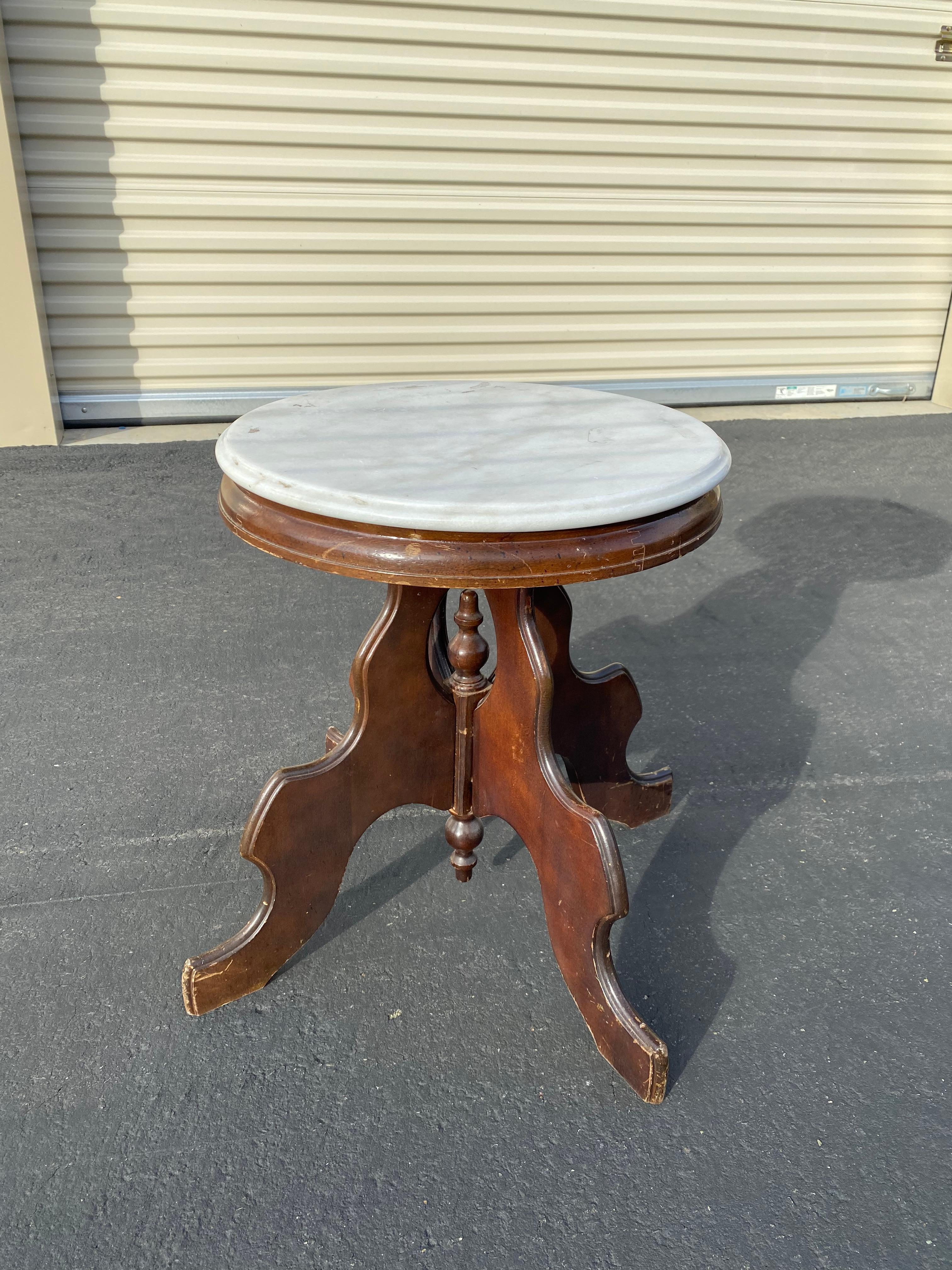 Antique Victorian Eastlake parlor table, circa 1880s. Made from walnut with an oval white marble top. Base features a turned center support surrounded by four serpentine carved legs leading to castors.