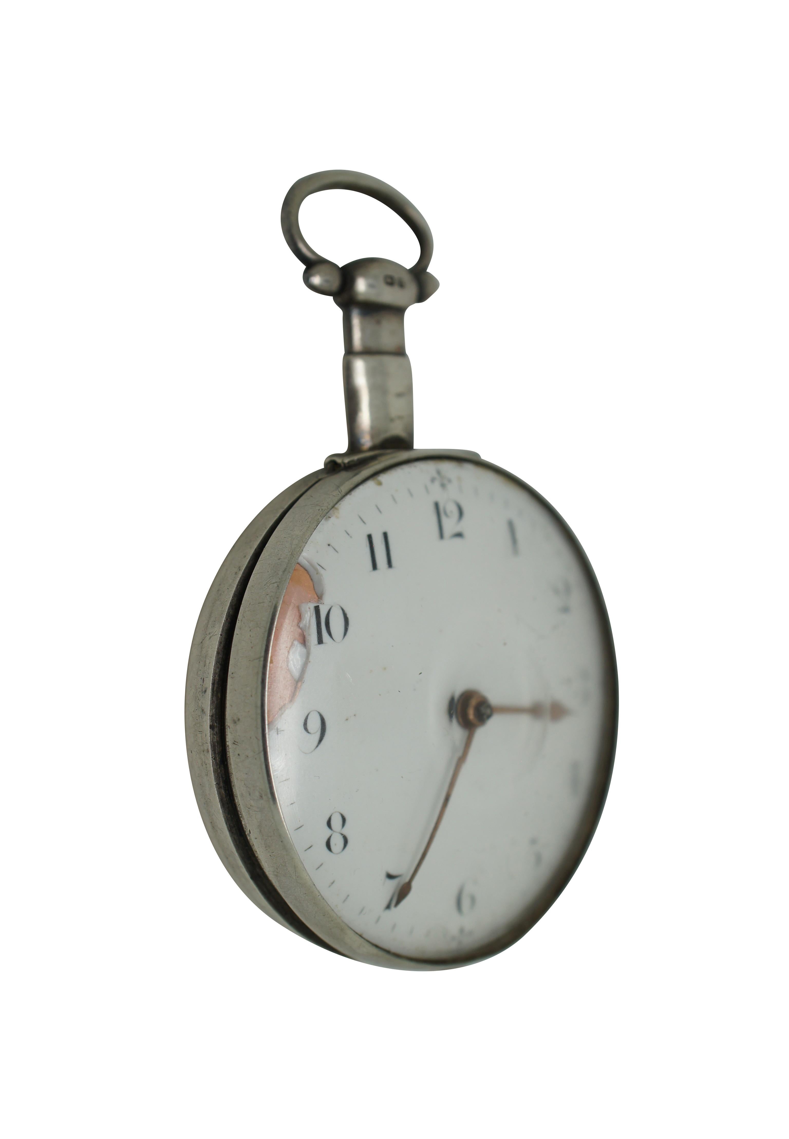 Antique early 19th century pocket watch. Sterling silver case with glass front. Swivel panel on reverse reveals key hole for winding. White porcelain face with copper hands, Arabic numeral and fleur de lis accents at the quarter hours. City mark and