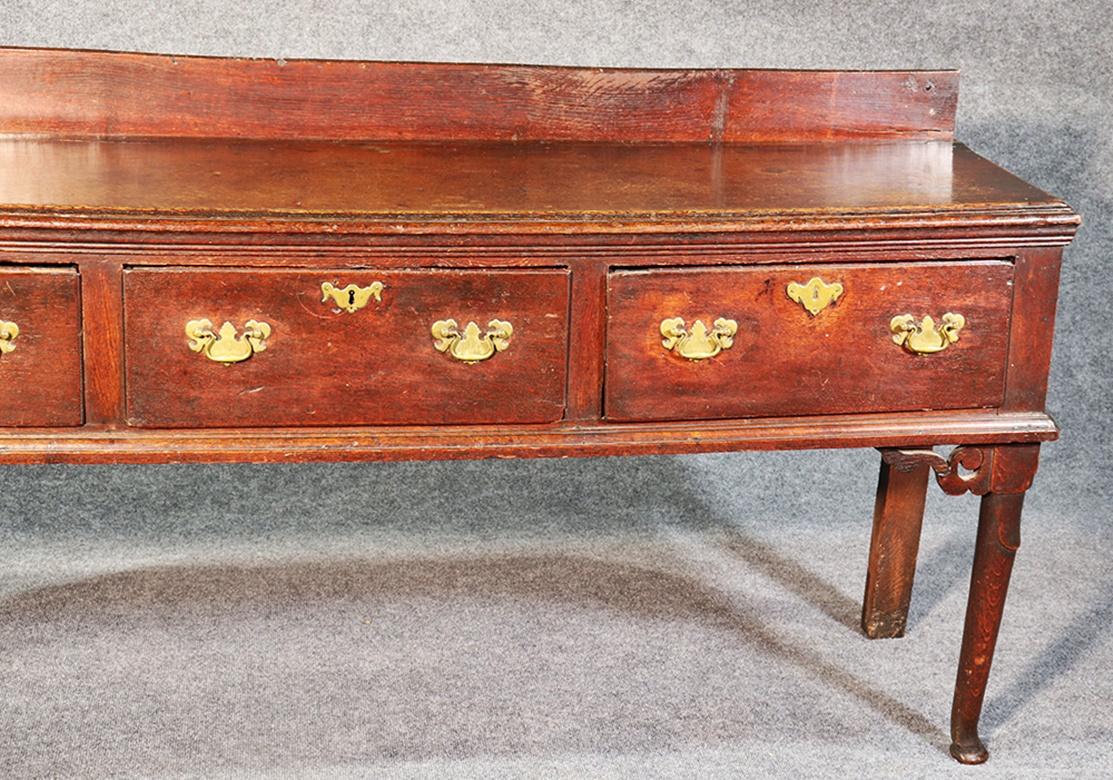 This is an early 1800s era Georgian style solid oak sideboard or hunt board. The piece has a lot of time-worn character and the hardware is incredible. Great piece for a mud room or antique home.