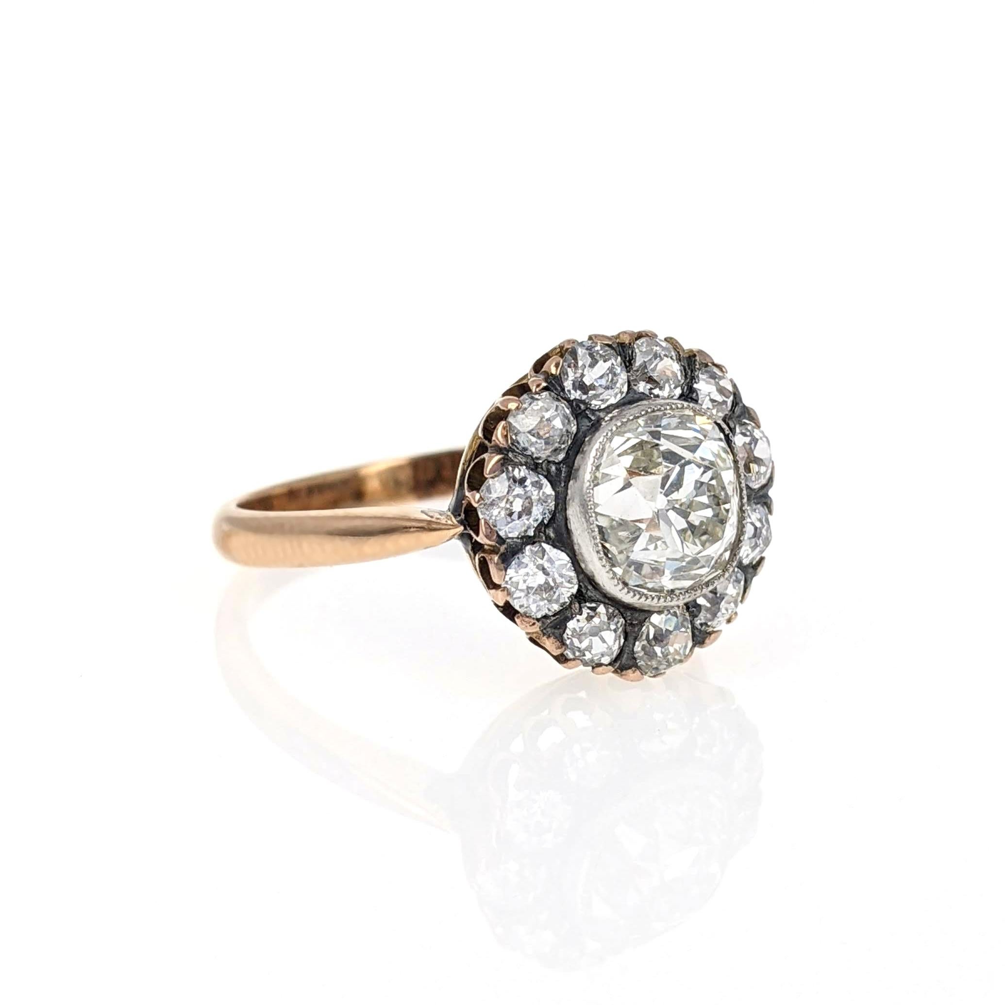 This charming antique cluster ring centers upon an old mine-cut diamond weighing 1.83 carats and is further surrounded by eleven old-cut diamonds. It is expertly crafted in 18 karat rose gold and topped with silver. Size 7.75.