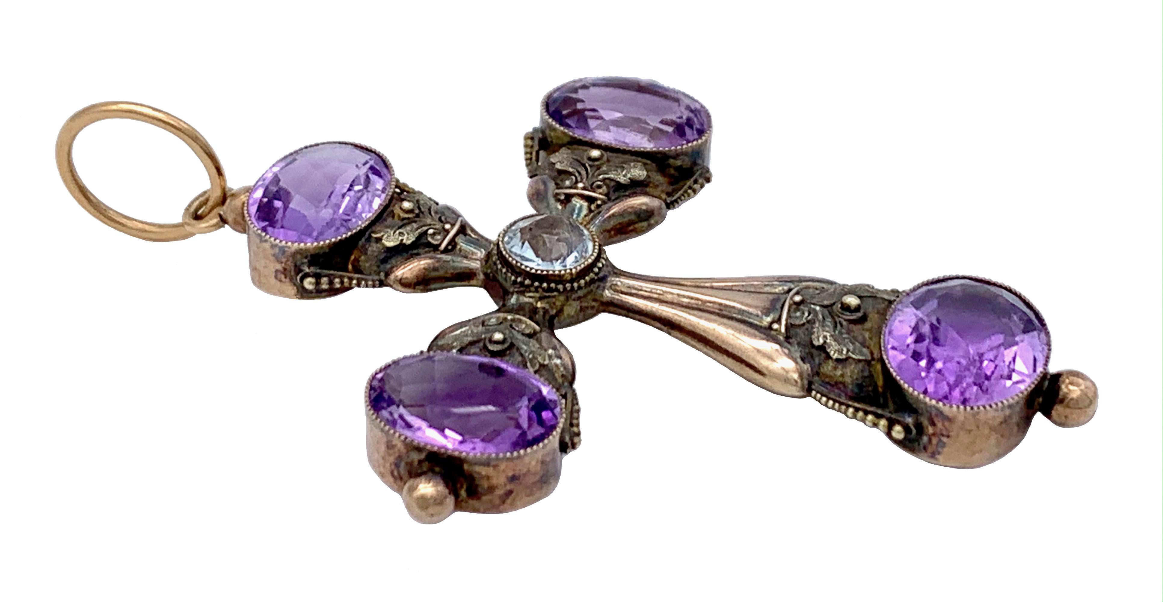 This elegant cross is set apart by it's delicate colour scheme. The oval amethysts and the central round aquamarine are accentuated by two coloured gold work. 
The golden ring from which the cross is suspended has a diametre of 1.2 cm. 