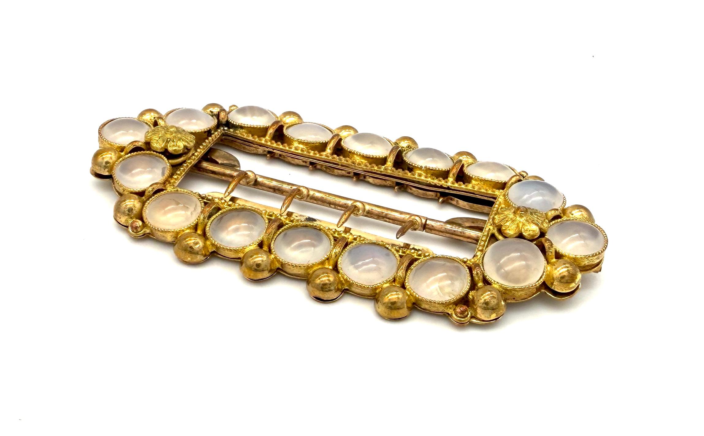 Cette superbe boucle de ceinture ancienne a été créée en 1835 environ. Elle était destinée à être portée autour du cou. Il est serti de 16 cabochons ronds en calcédoine. Les pierres sont serties dans une boucle en métal doré. 
Chaque calcédoine
