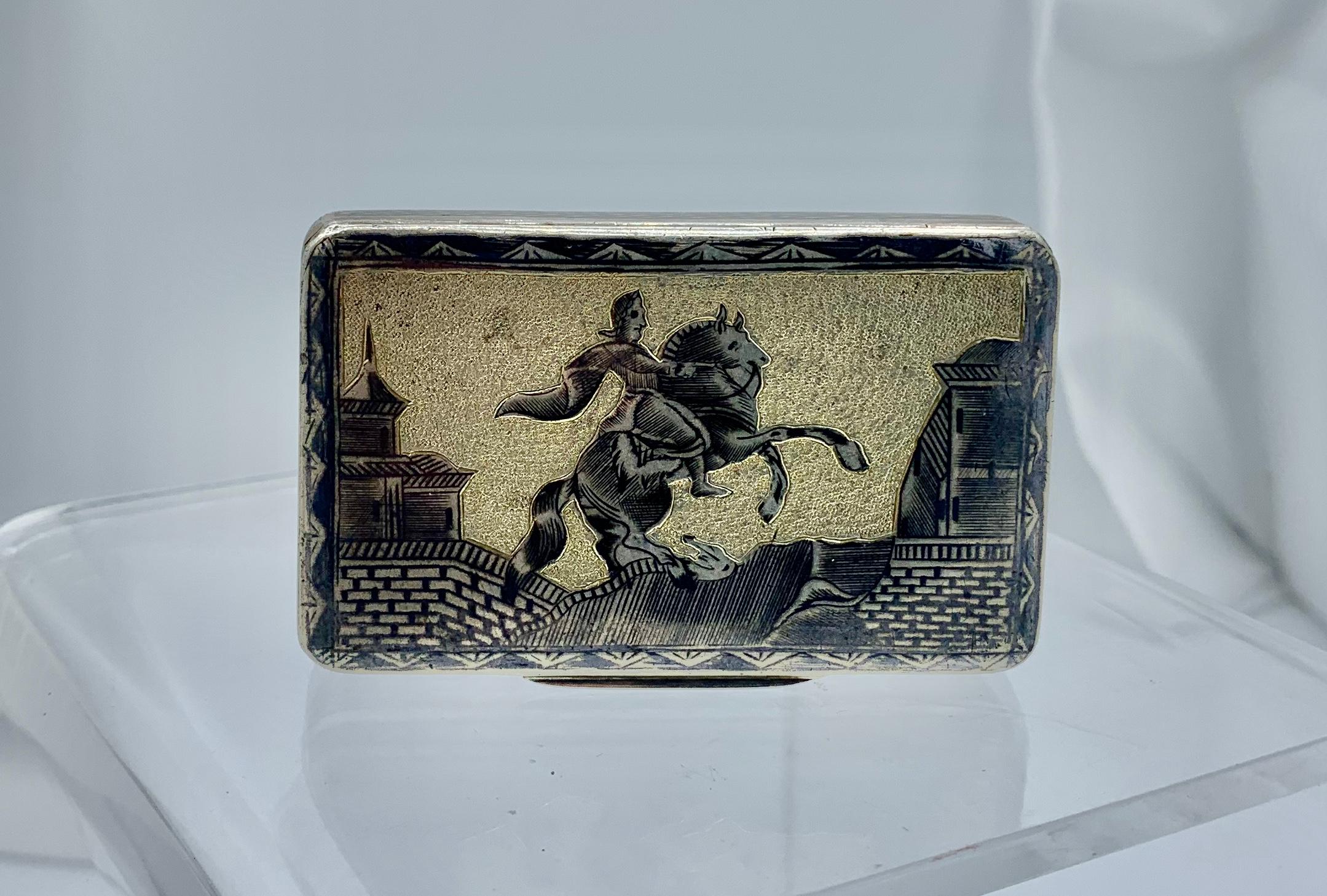 This rare Russian Silver Niello Enamel Box is dated 1841 and has full Russian Hallmarks.  The box has a stunning raised engraved image of a man on horseback entering a village.  On the reverse is a river village scene with a boat on the river.  The