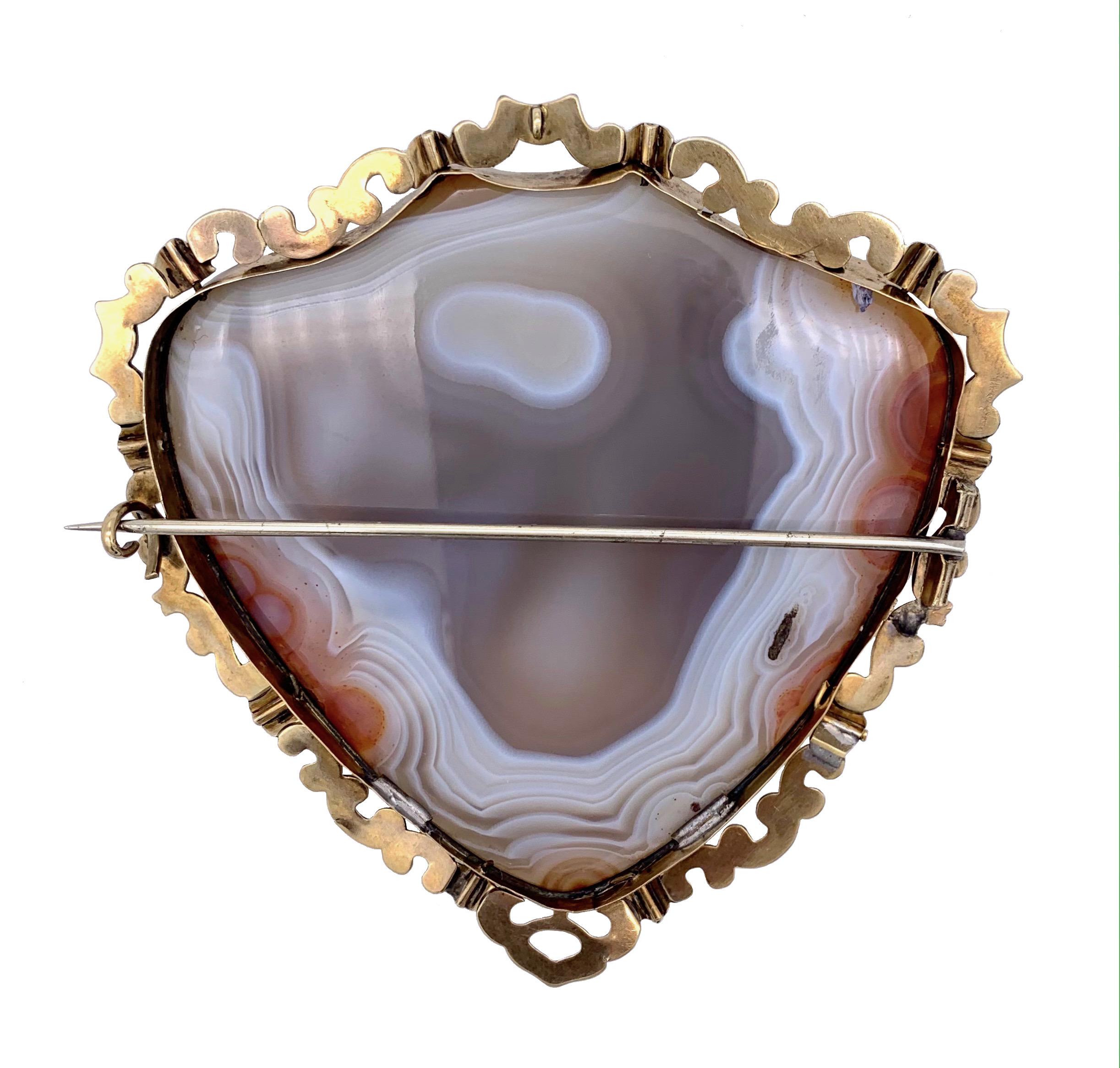 This beautiful Victorian brooch has an amazing size.
The agate is bevelled and carved in the shape of a shield. The beautiful stone is mounted in a setting decorated with golden scrolls. The large pin is made out of metal for added strength.
