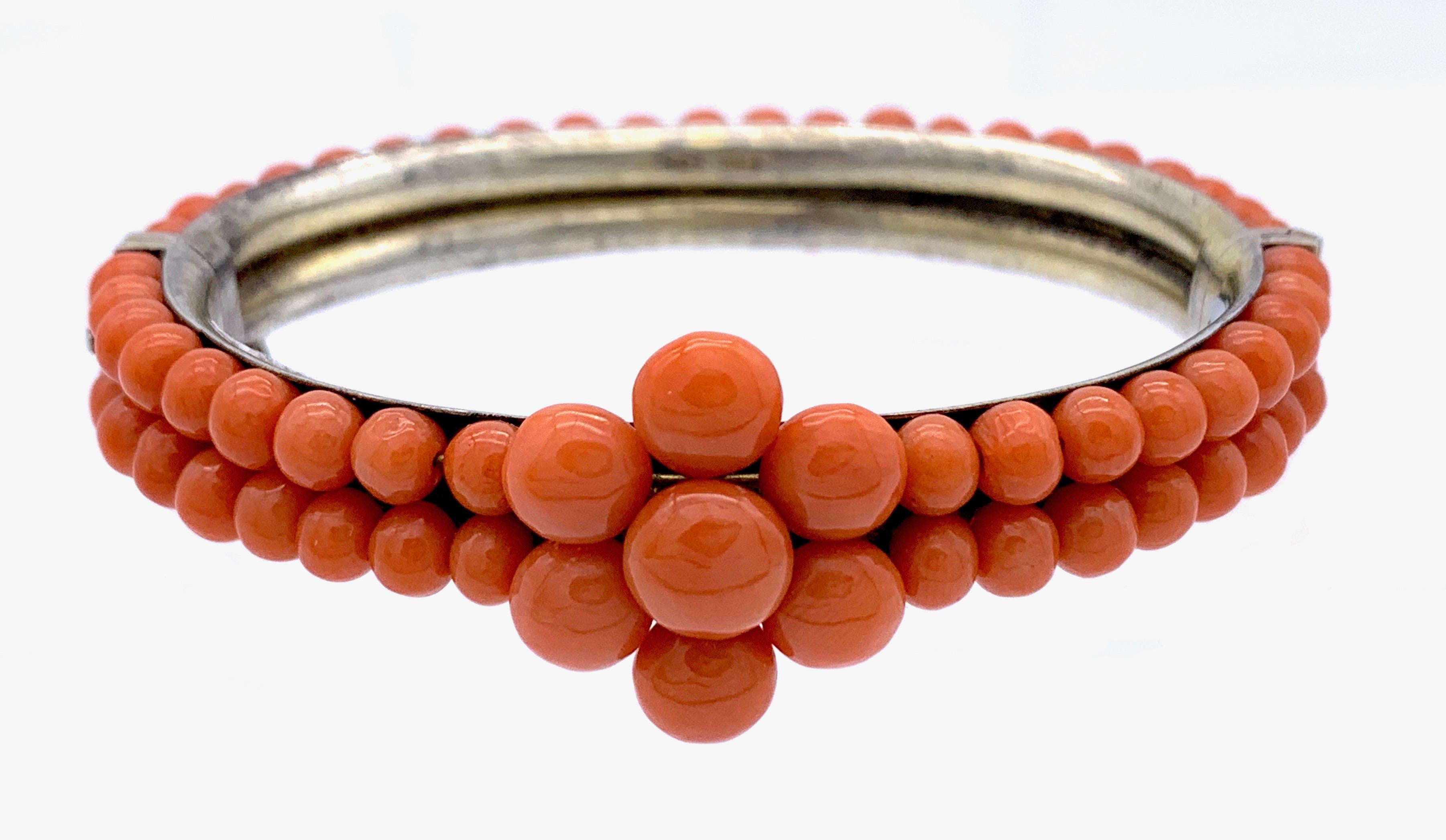 This lovely coral bracelet comes in fine condition with its safety chain. Two rows of coral beads have been mounted on a silver bracelet  that has retained remains of the old gilding. The centre of the
bangle is decorated by a flower made up from