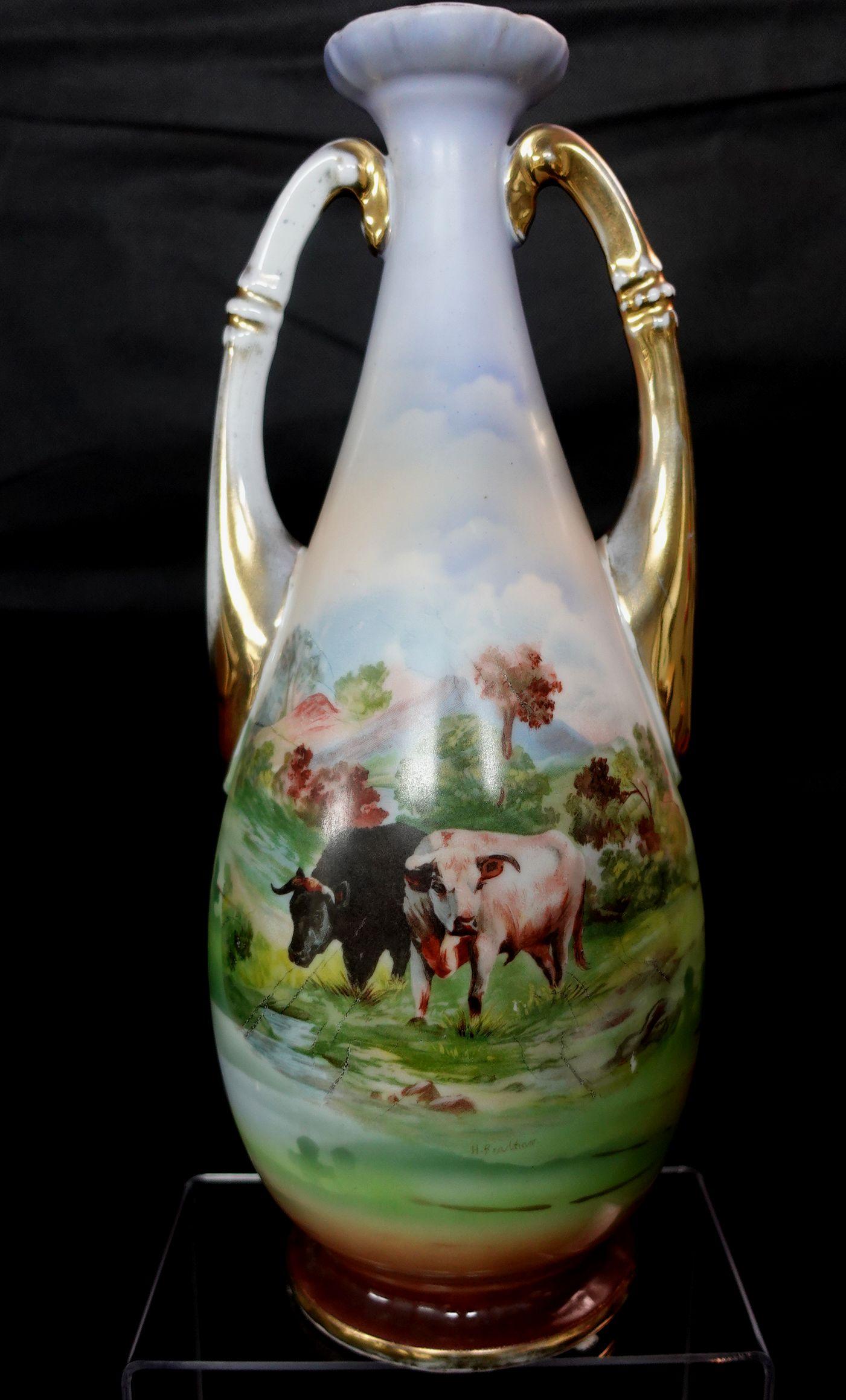 Antique 1890s Victoria Austria Vase. Comprising Austrian porcelain vases with hand-painted decorated scenes of cattle watering. Measure: Height 14 inches.
    
