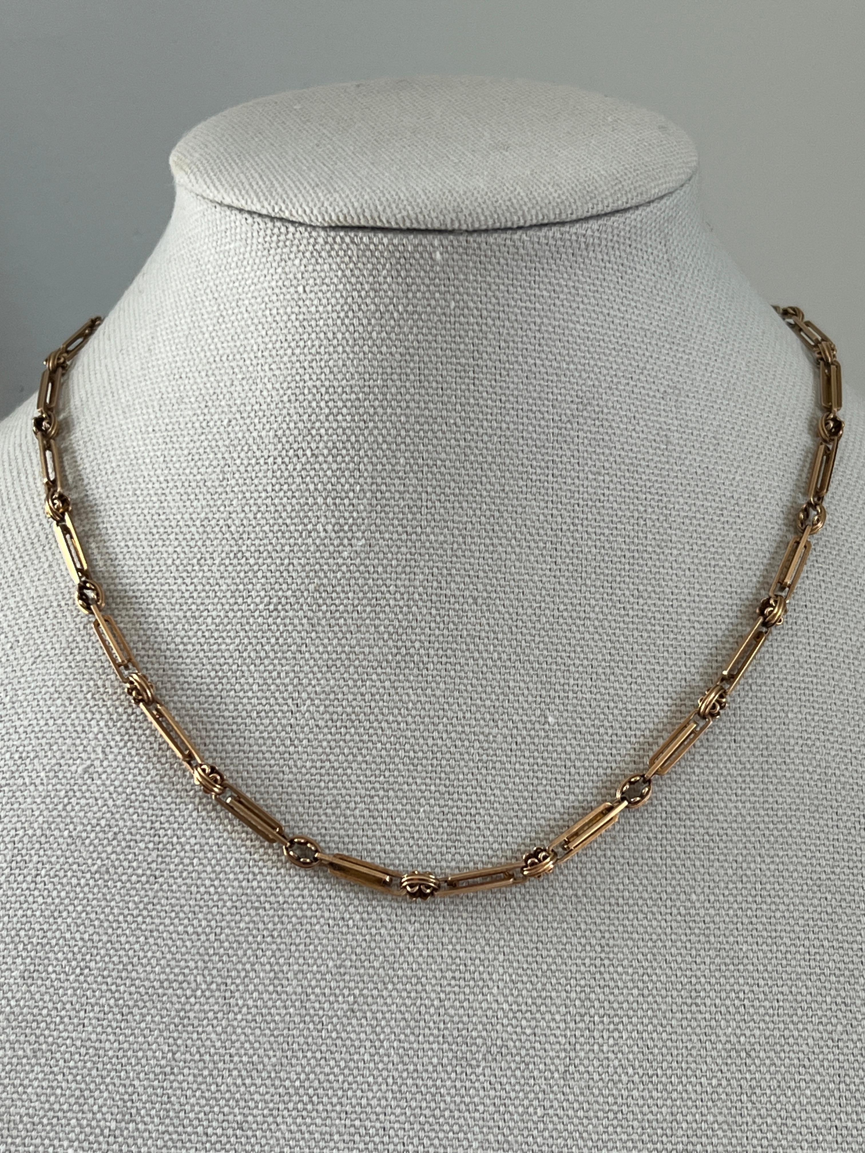 This antique 1885 Victorian ladies watch chain turned necklace is crafted from 14 karat yellow gold and features a distinctive 19-inch trombone link design, a popular style in the late 19th century known for its sturdy and elegant construction.