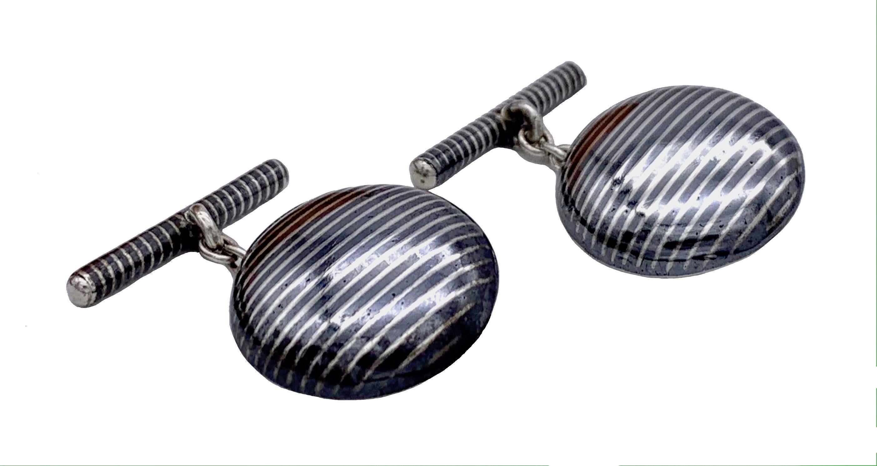 This elegant pair of silver and niello cufflinks is decorated with a finely executed geometric line ornament.  

The cross bar measures 2.5cm.
 The chain measures 1,9cm, it could be shortened if so desired.