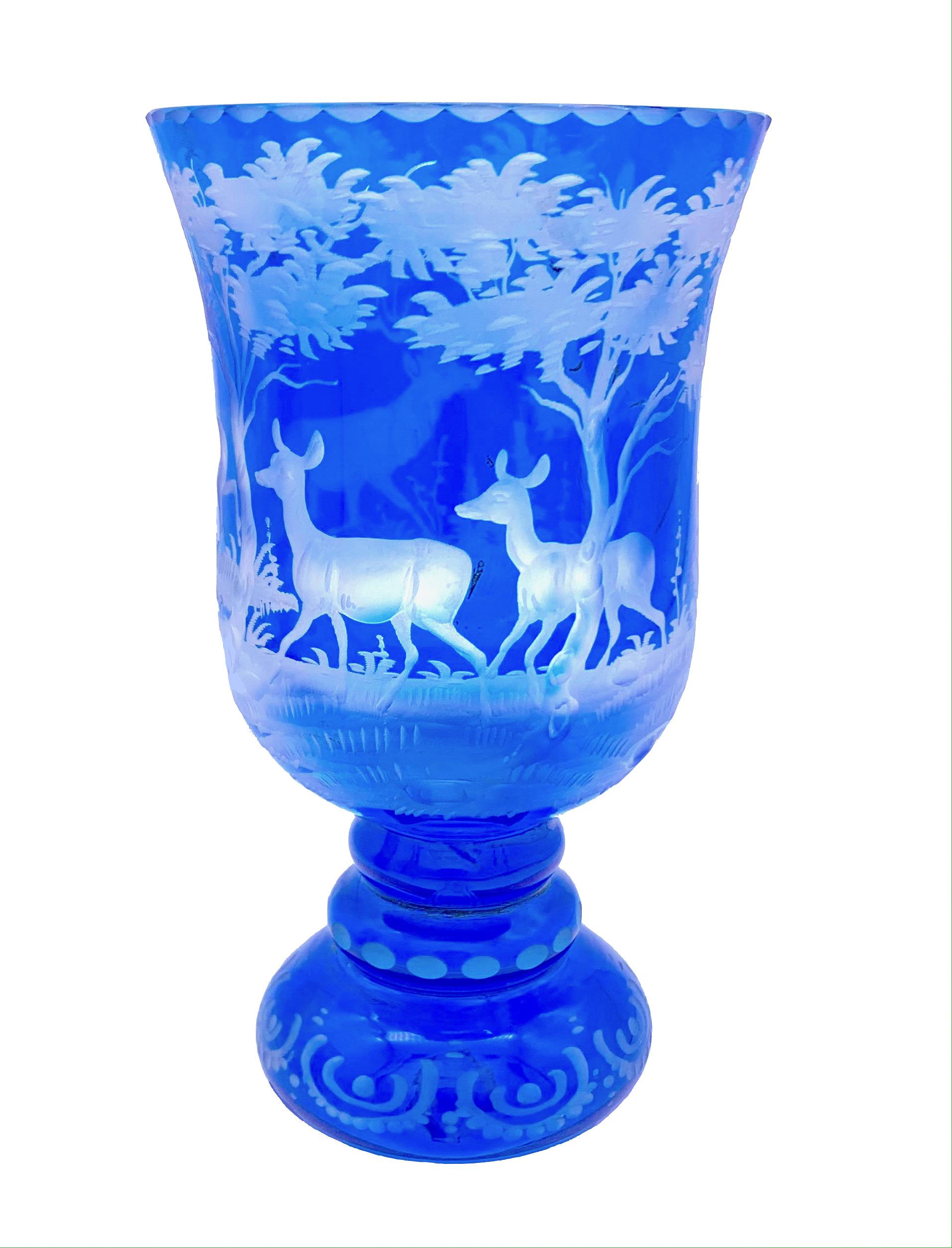 These two wine glases of blue and white crystal glass have been delicately engraved and show dear in a forest clearing.
